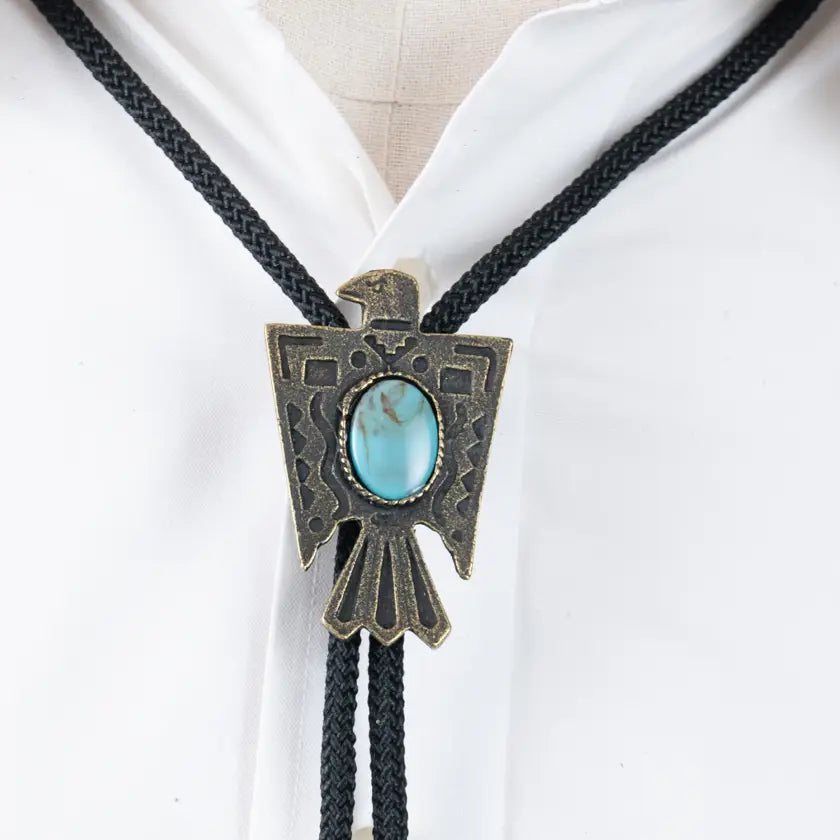 A close-up of a Forager Provisions Thunderbird Blue Stone Bolo Tie worn over a white shirt, showcasing its silver thunderbird pendant and the exquisite turquoise stone at its center.