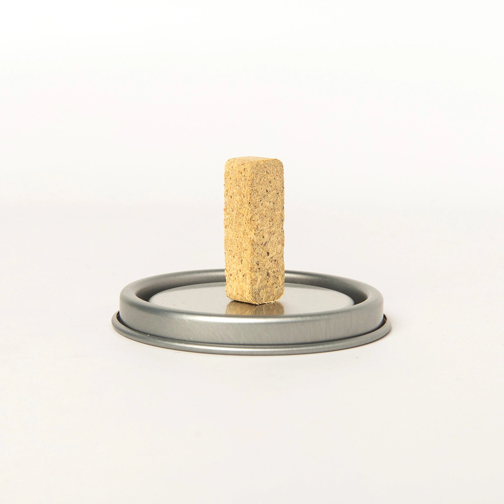 Brown Piñon incense brick by American Heritage Brands displayed upright on a silver jar lid with a clean white background.