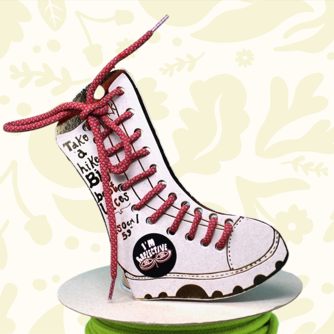 Ark’s Big Boot Laces in red and silver sit on neon green yarn, blue sky and green field backdrop. Trendy shoelaces by Ark.