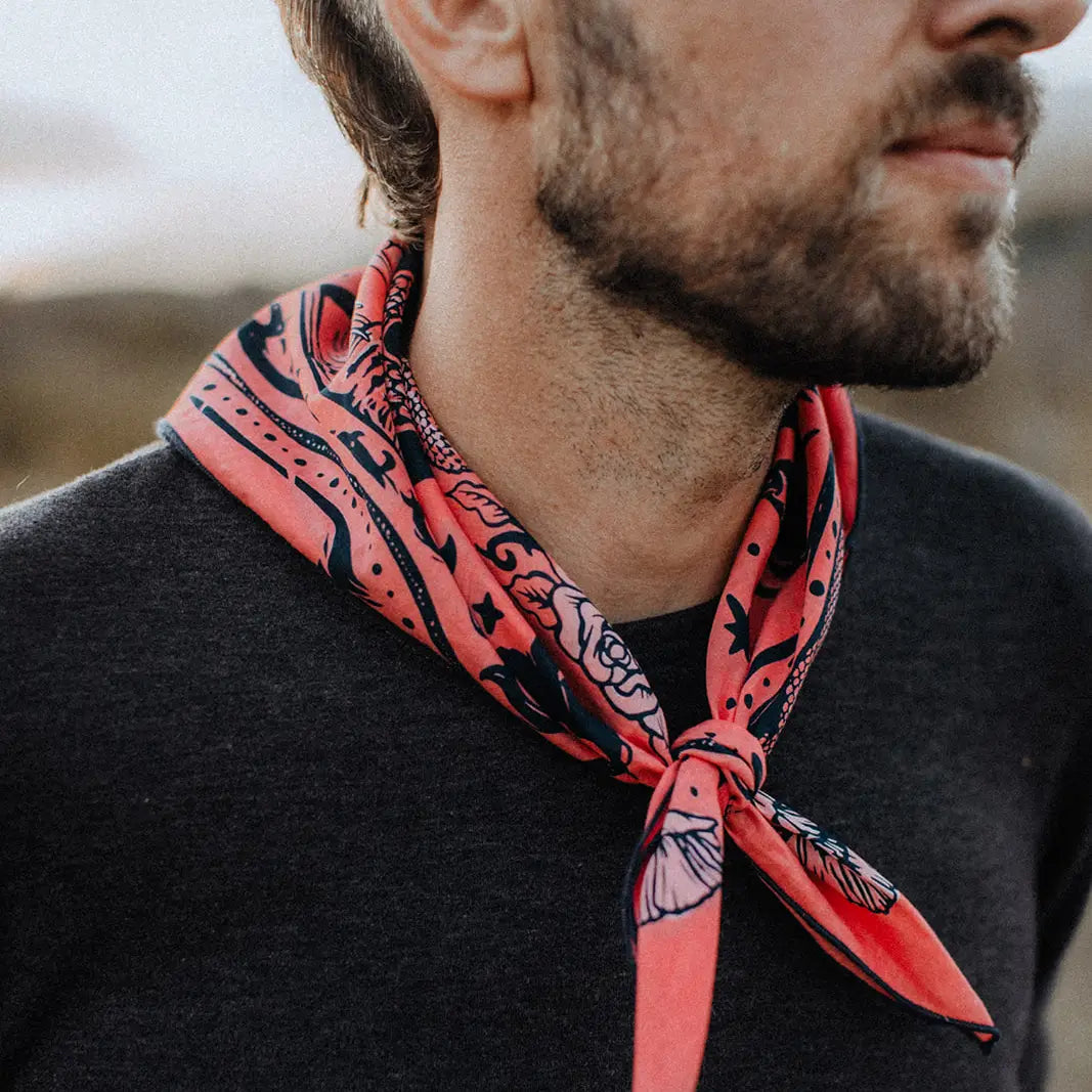Close-up of man outdoors in dark shirt wearing Bandit Bandanas “Rattle & Hiss” bandana covering lower face and neck.