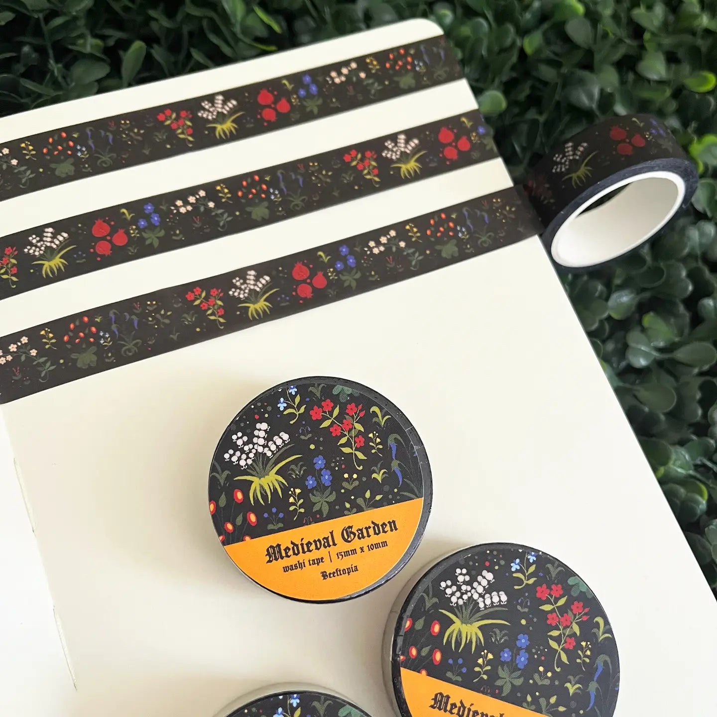 Beeftopia Medieval Unicorn Garden Washi Tape 15mm x 10m, decorative tape on notebook, with green leaves in background.