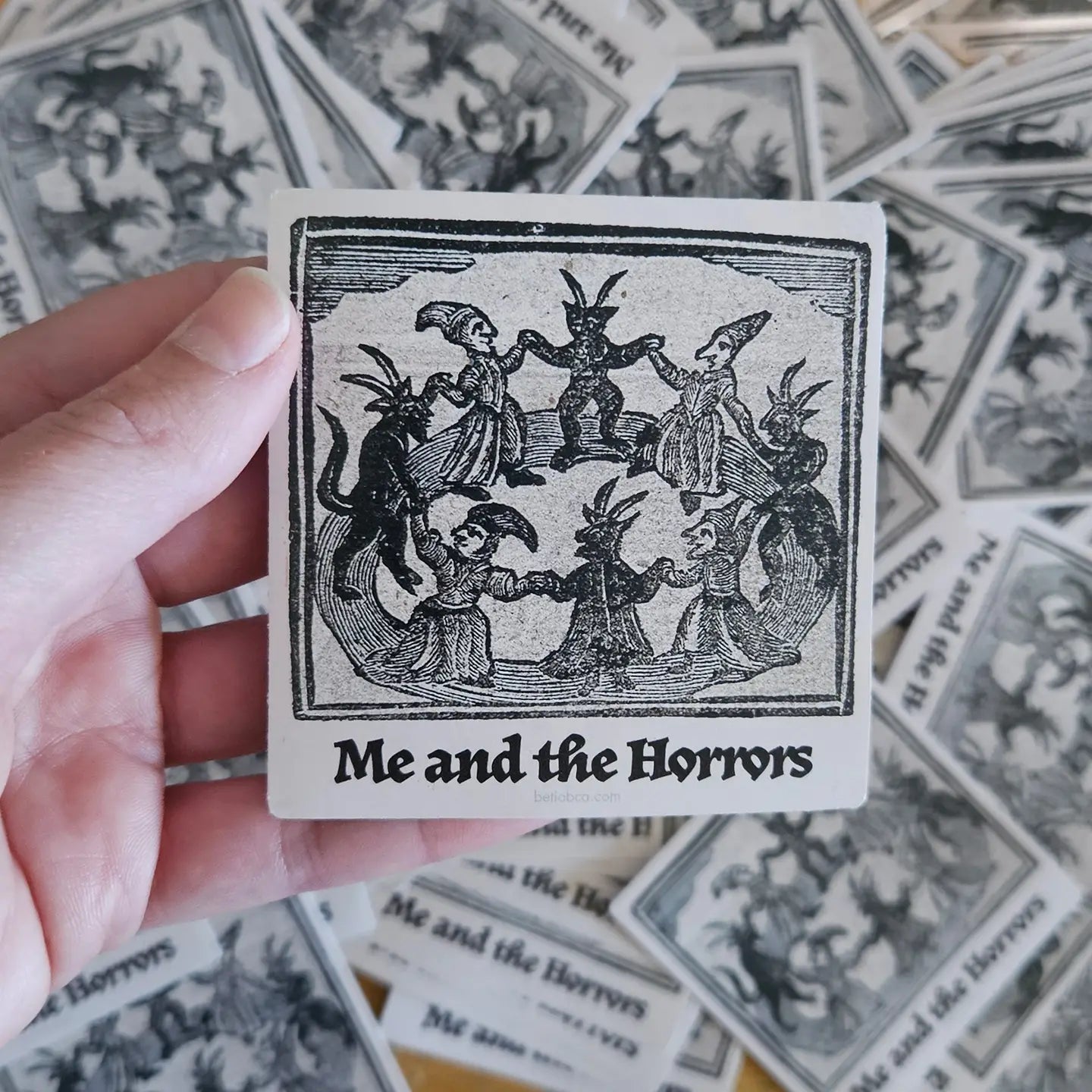 Hand holding Betiobca Vinyl Sticker—Me and the Horrors, with unique folklore dancing figures. Perfect for art sticker lovers.