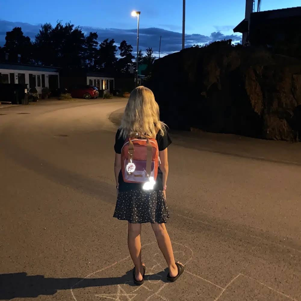 Forager Provisions LTD Firefly Sweden pink bunny reflector charm attached to a backpack on a girl at dusk