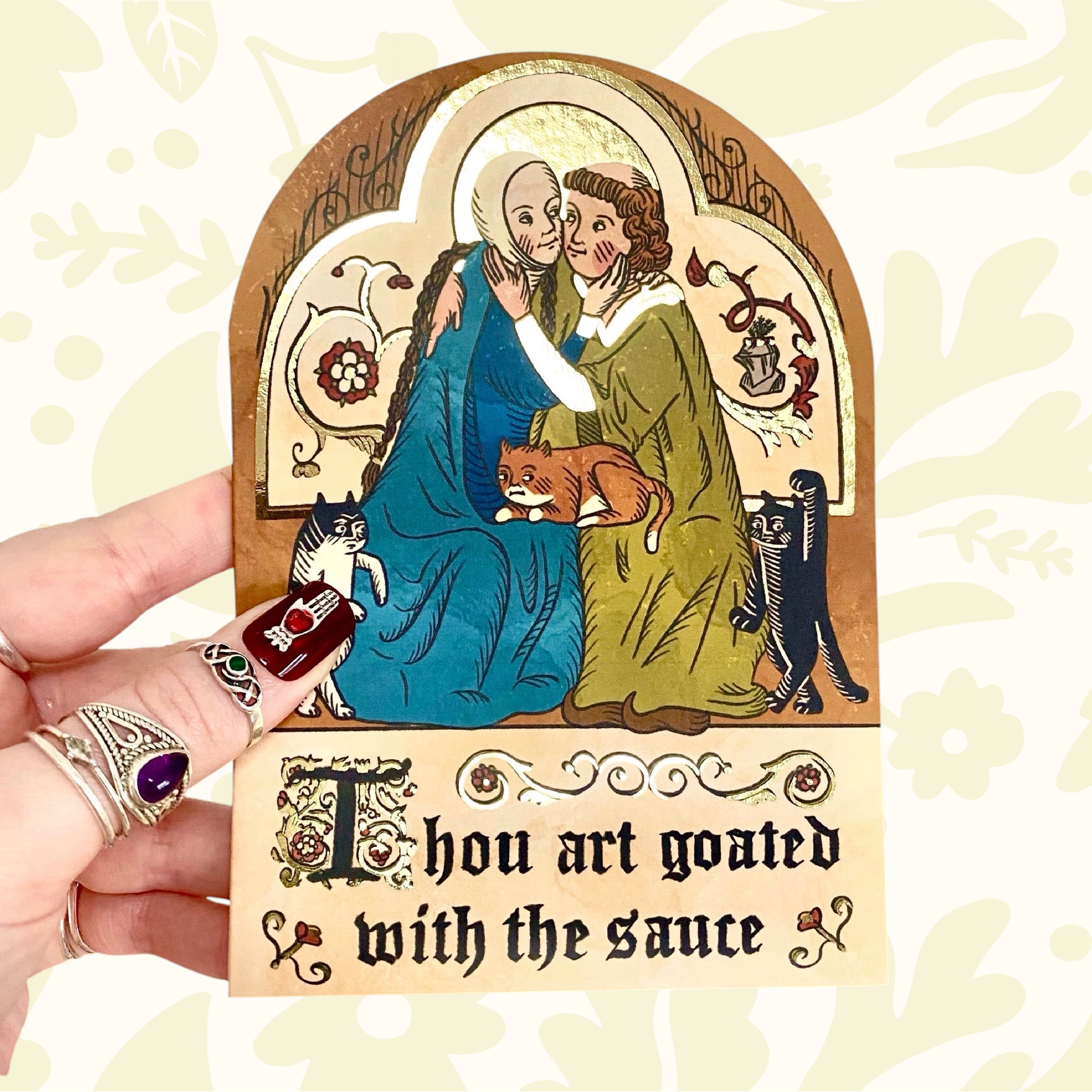Hand holds Clarice Tudor Medieval “Thou Art Goated” greeting card with two vintage figures, a cat, romantic unique design.