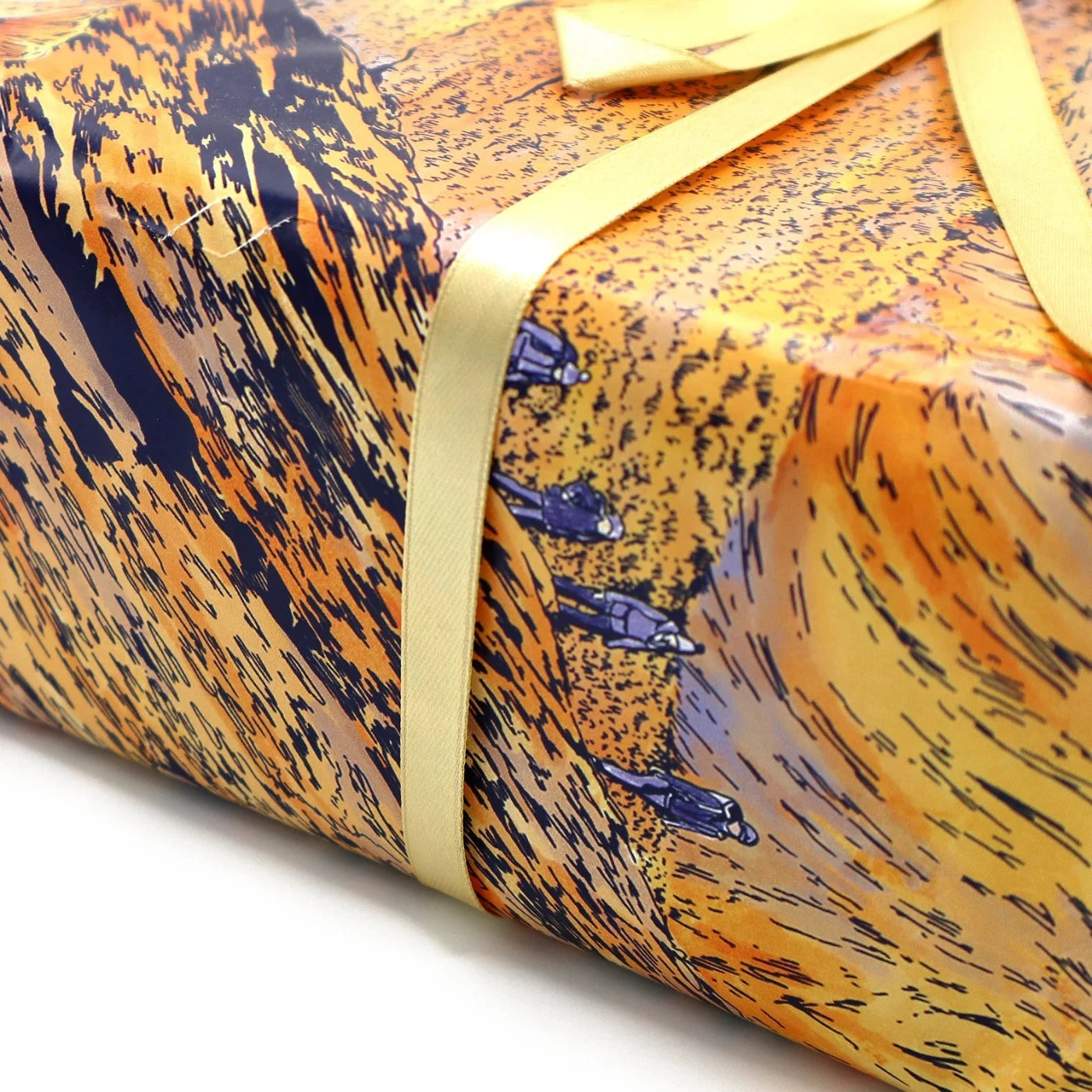 Up close image of a wrapped present in orange mountain theme paper with small details of hikers