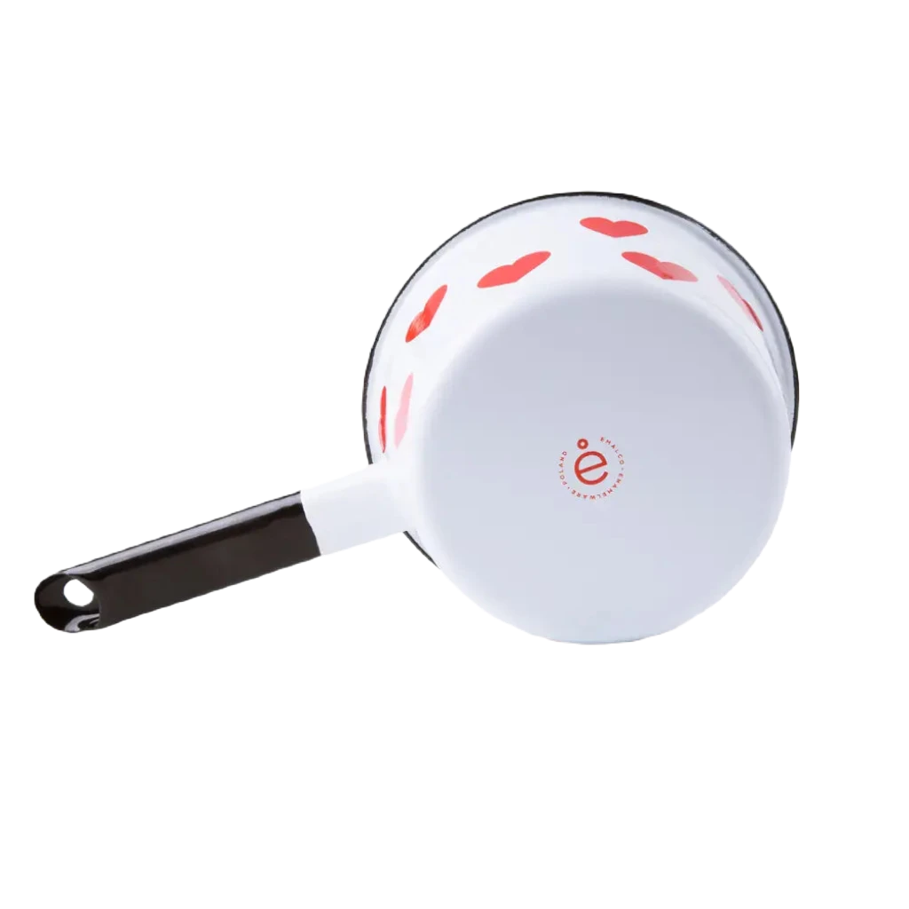 The Emalco Enamelware Enamel Heart Saucepan, featuring a white body with a black handle, is crafted from durable enamel material and adorned with charming red heart patterns. Pictured on a white background, it’s the perfect addition to your Emalco Enamelware collection.