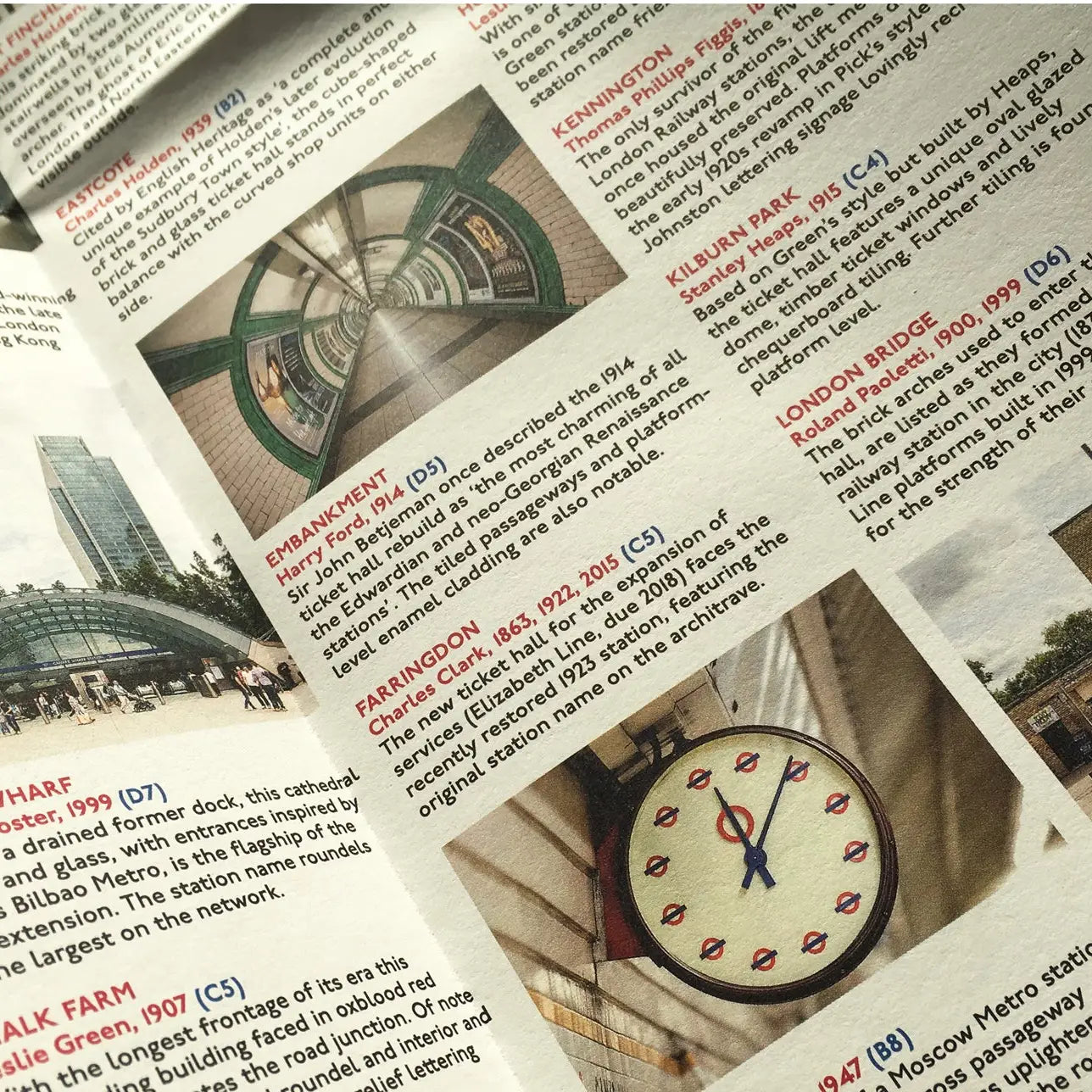 A close-up of an open Blue Crow Media London Underground Architecture Map displaying articles and photographs of London Underground stations, showcasing the intricate transport design and featuring a clock at Farringdon.