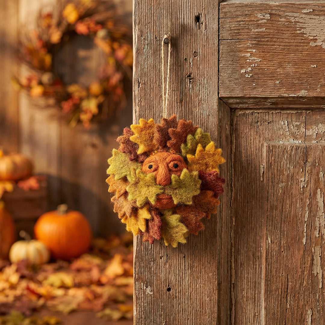 Forager Provisions LTD handcrafted felt Green Man hanging decoration with vibrant autumn leaves on a rustic wooden door.