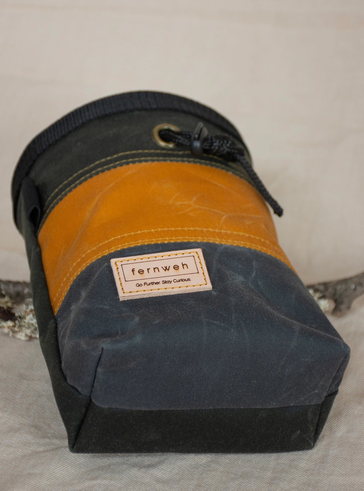 The Fernweh UK Waxed Canvas Rock Climbing Chalk Bag in Forest/Sand/Scree sits on a neutral surface, stylish and durable.