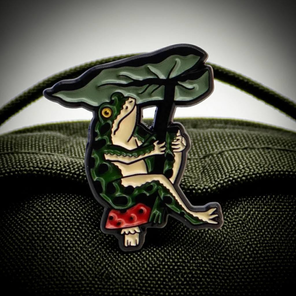 Forager Provisions LTD Stay Home Club enamel pin featuring a green frog holding a leaf umbrella while sitting on a mushroom