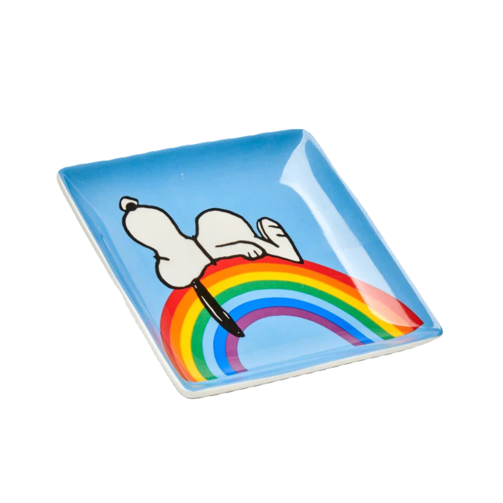 A blue box features a drawing of Snoopy lying on a rainbow, with text that reads "Magpie + Peanuts comic strip" at the top and "Good Vibes Trinket Tray" at the bottom.