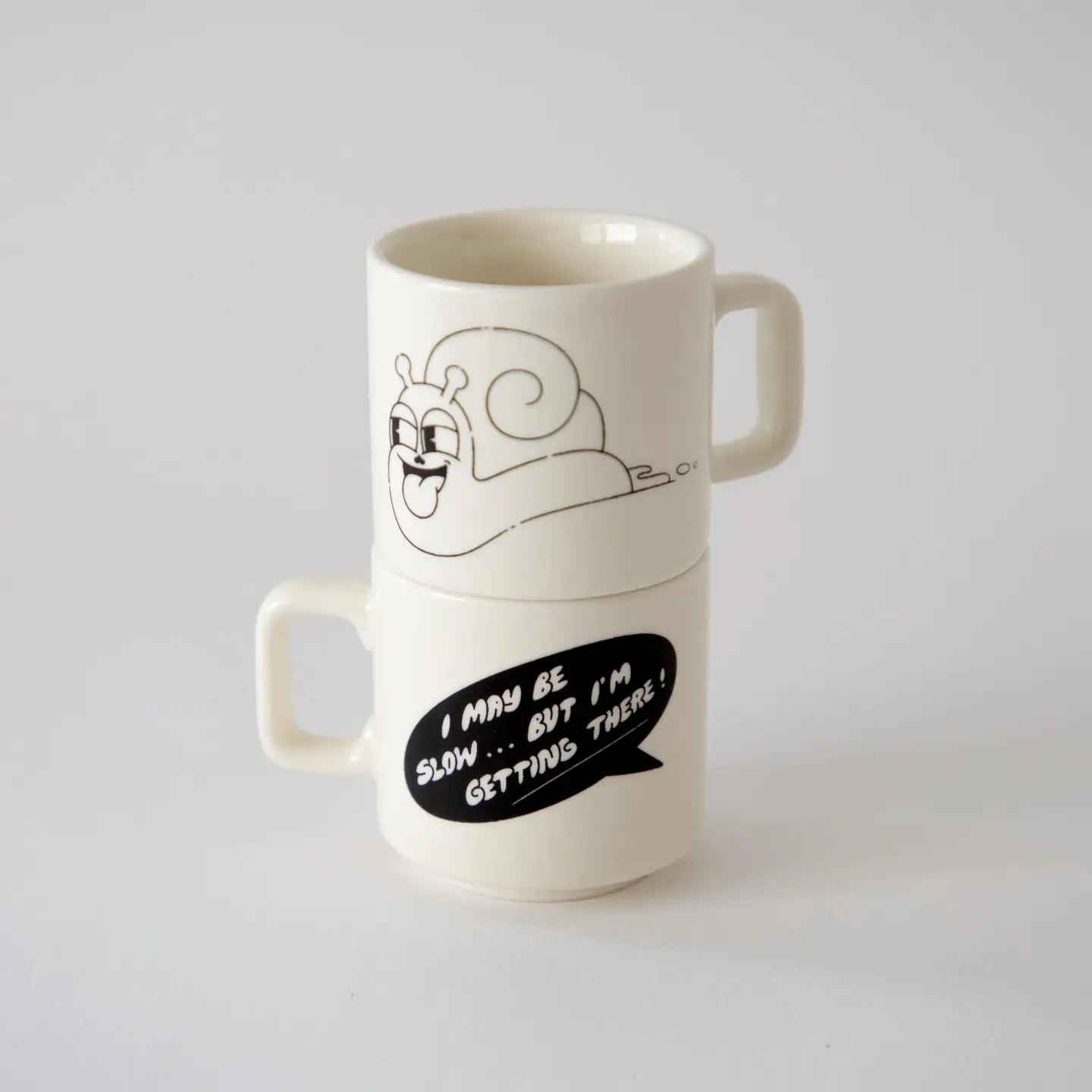 Third Drawer Down x Hattie Stewart espresso cups set—two white cups featuring snail art, text: “I may be slow... but I’m getting there!”.