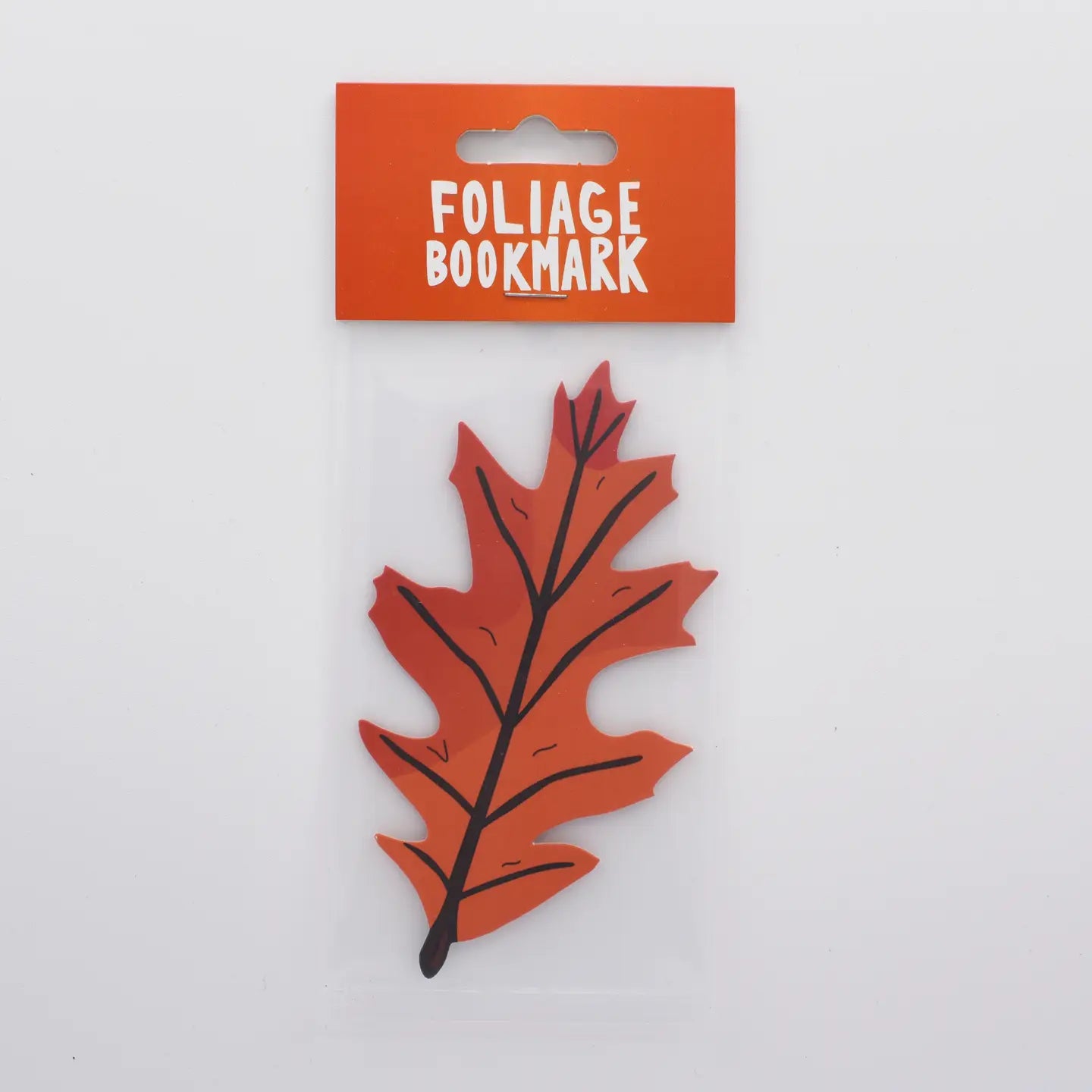 Plastic package containing a Humdrum Paper double-sided autumn leaf die cut bookmark, perfect for fall book lovers.