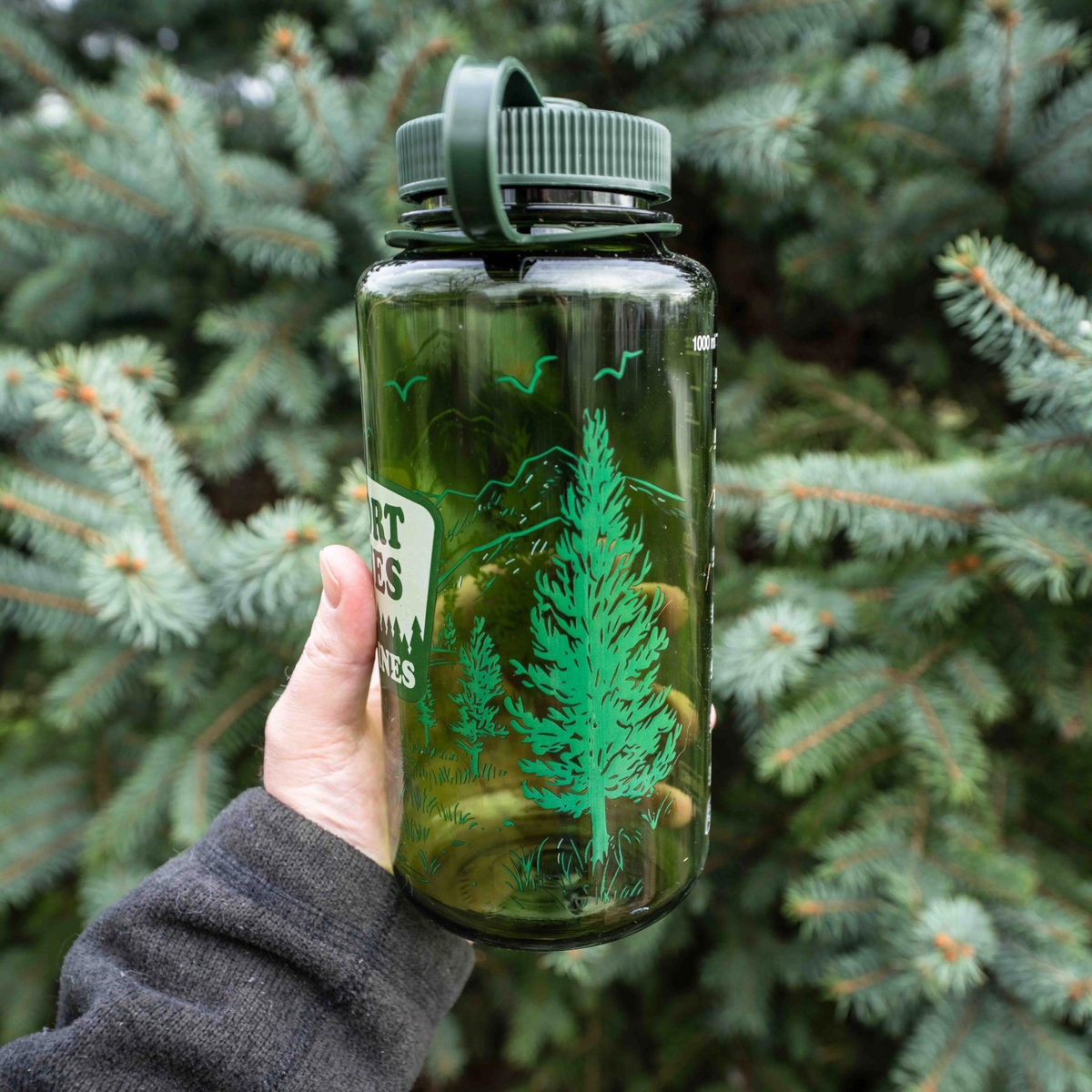 Forager Provisions LTD green 32oz Nalgene water bottle with Snort Pines Not Lines graphic held against pine branches