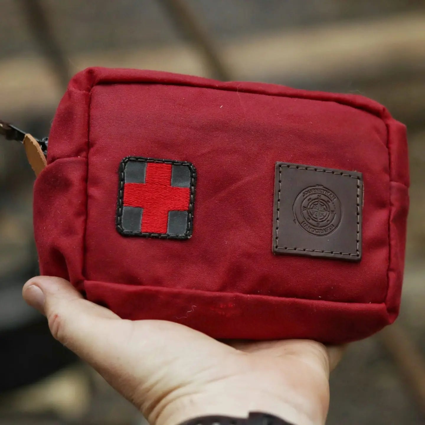 Hand holding Journeyman Craft First Aid Kit Belt—compact red pouch with medical cross and patch, perfect for emergency safety.