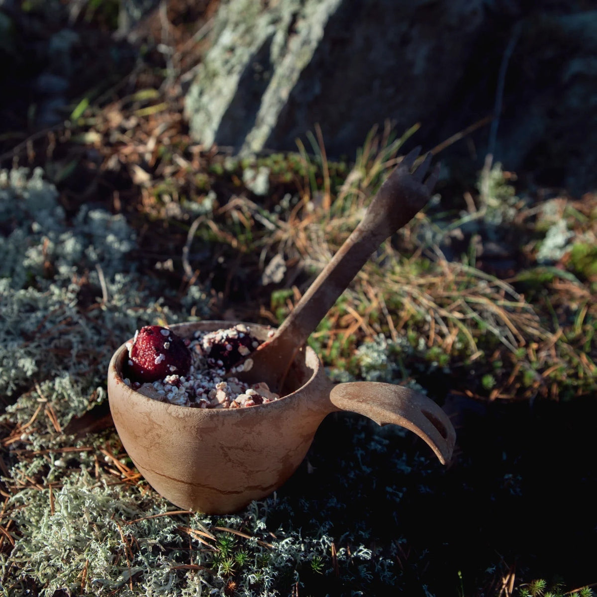 Forager Provisions LTD Kupilka 225 long brown spork in a wooden cup with oatmeal on a mossy forest floor