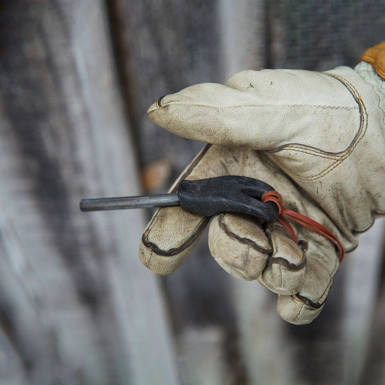 Kupilka Firesteel 8 Brown held by a gloved hand—top survival fire starter, reliable outdoor gear for camping and emergencies.