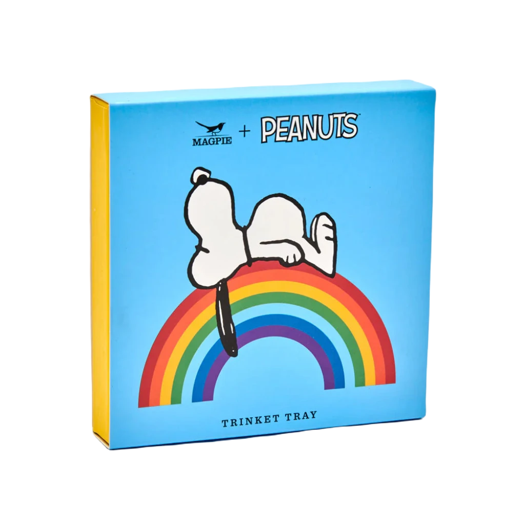 A blue box features a drawing of Snoopy lying on a rainbow, with text that reads "Magpie + Peanuts comic strip" at the top and "Good Vibes Trinket Tray" at the bottom.