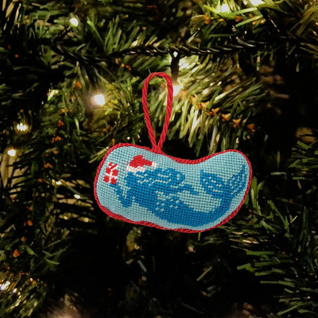 Decorative ornament with blue mermaid design hanging on a Christmas tree