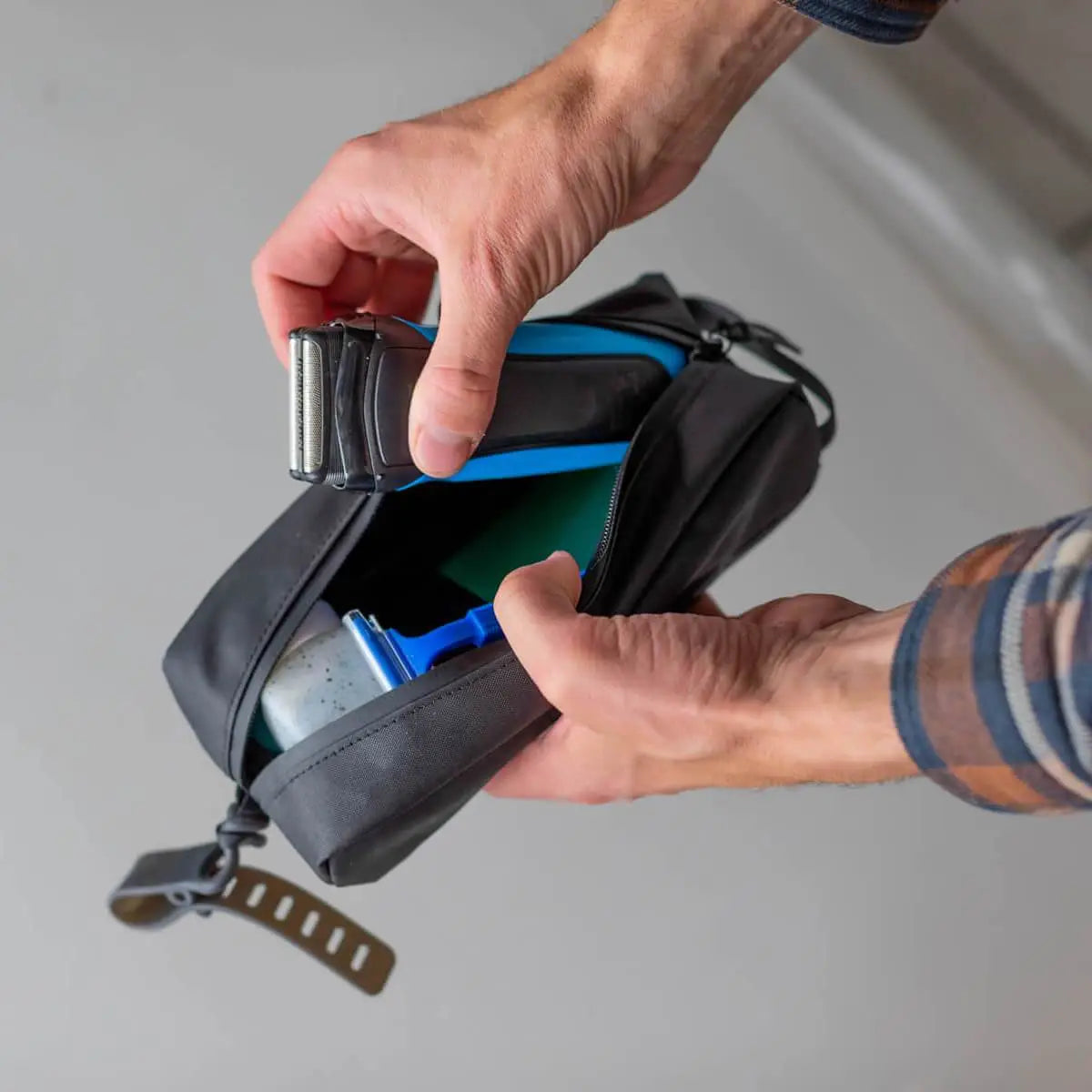 Person opening a black bag with a gray background