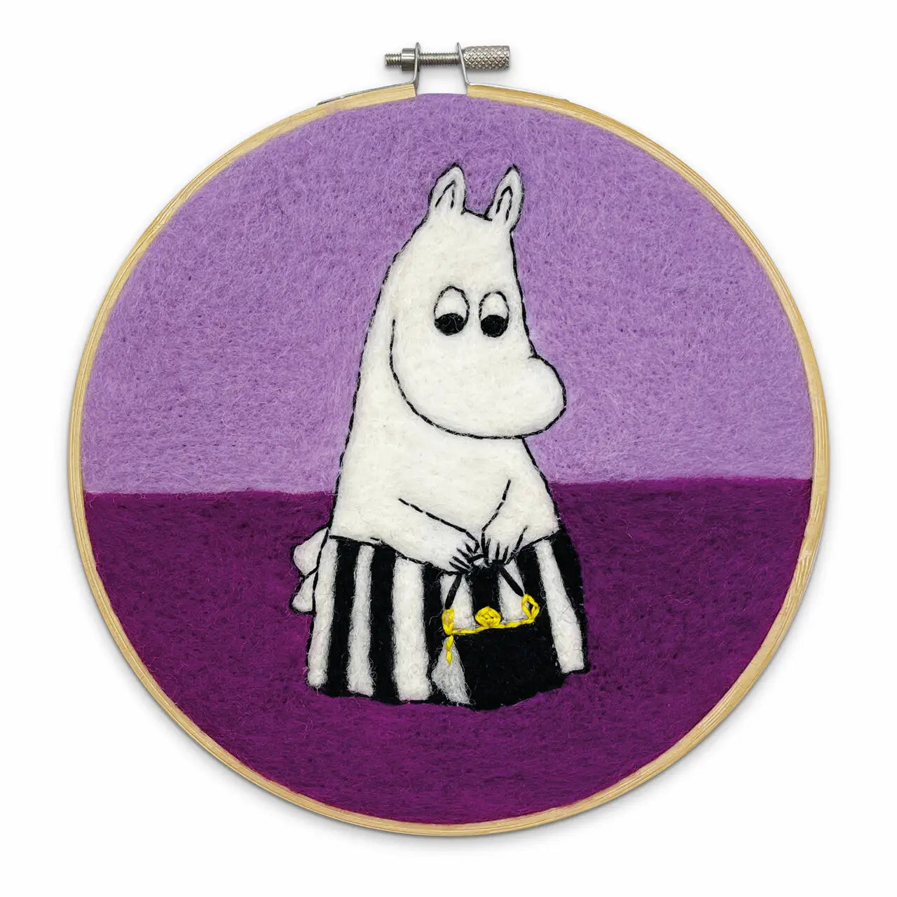 Embroidery of a white cartoon hippo character holding a bucket with something yellow on a purple and lilac background. This charming design evokes the quaint style of "Moominmamma Thinking" and fits perfectly within The Crafty Kit Company's selection, specifically as "The Crafty Kit Company Moominmamma Thinking Cross Stitch.