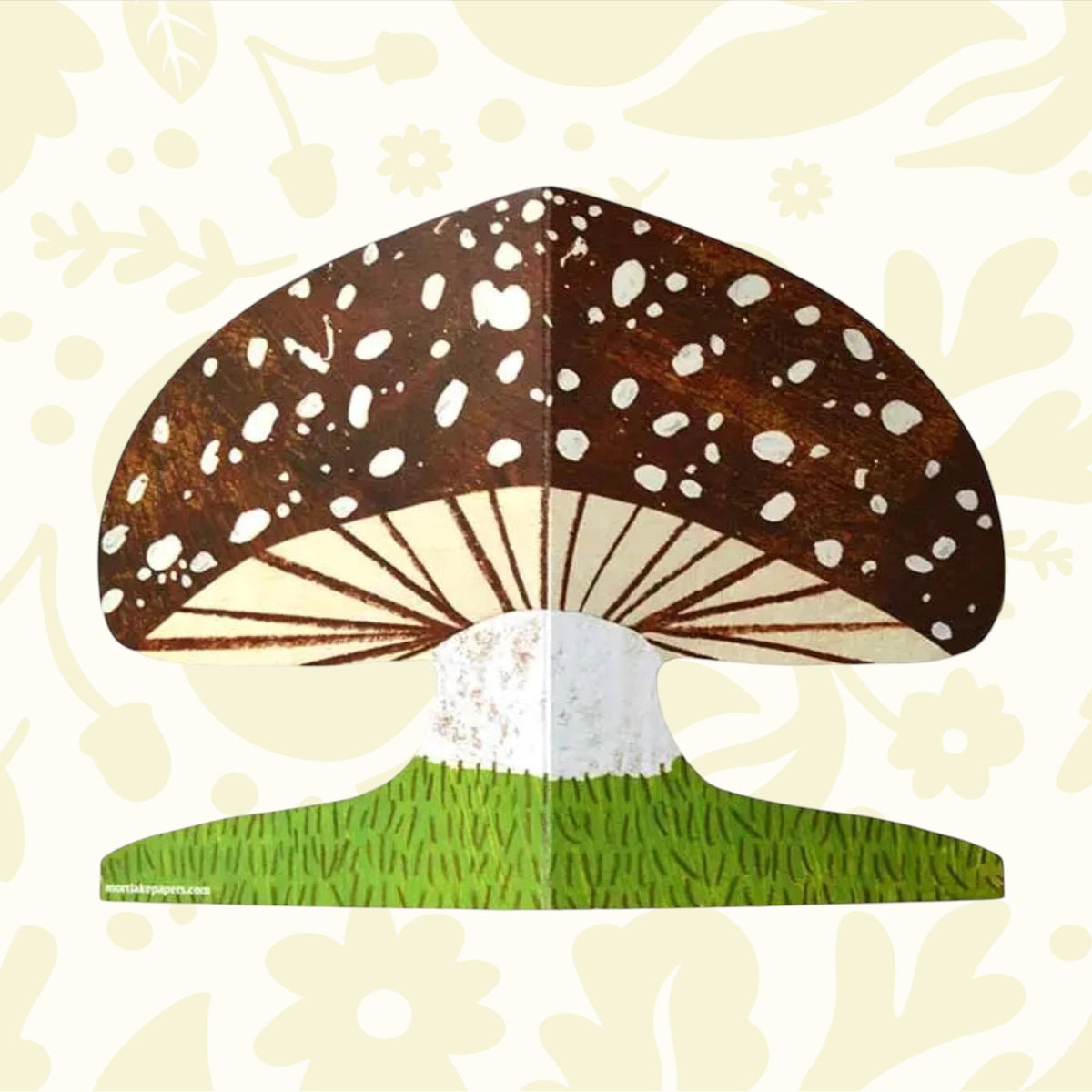 laid out mushroom shaped card with brown cap and spots growing from green grass at the bottom.