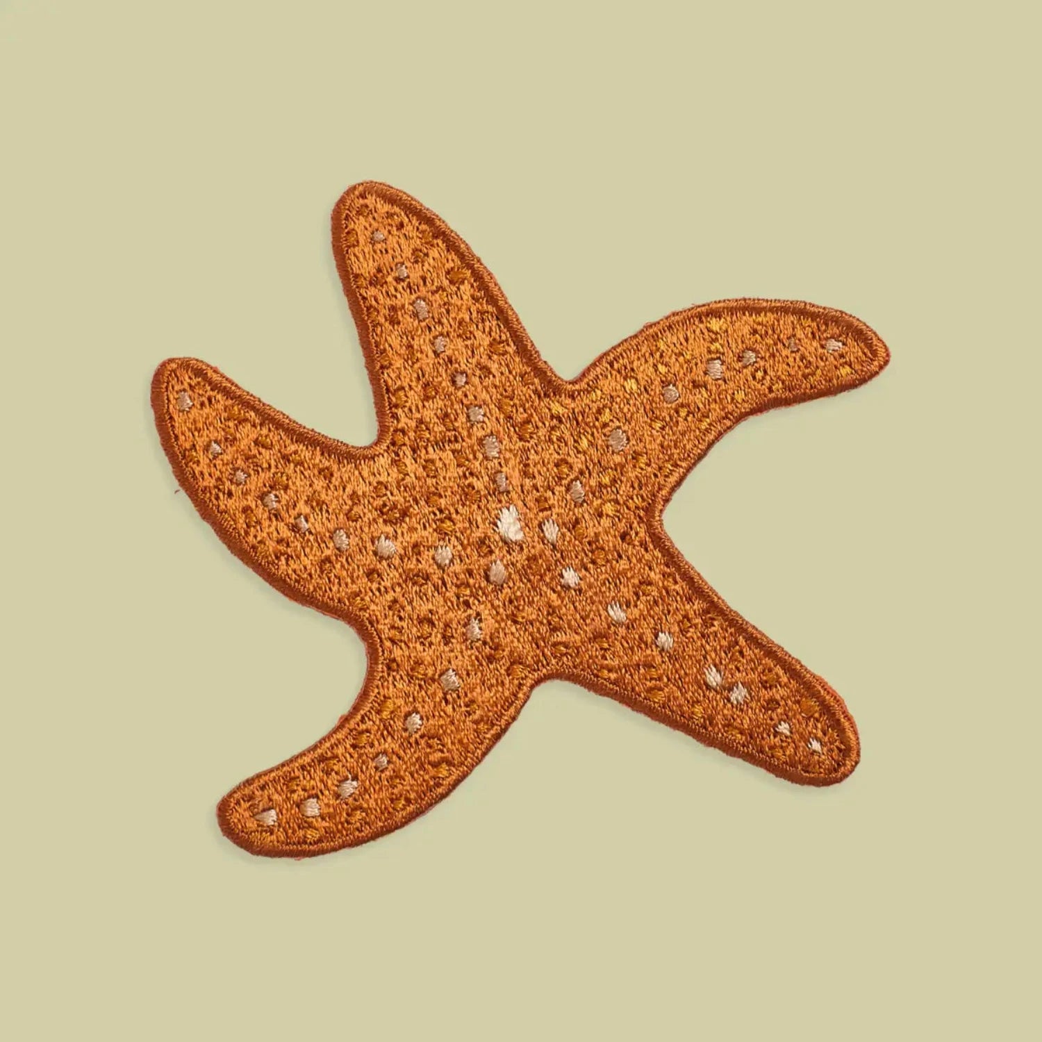 Mustard Beetle Ochre Sea Star iron-on patch with white embroidery, beige background—unique ocean-themed accessory for jackets.