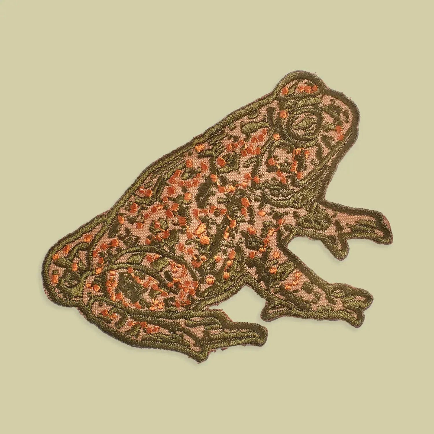 Green and orange frog iron on patch, Mustard Beetle Toad design, embroidered for jackets or bags on beige background.