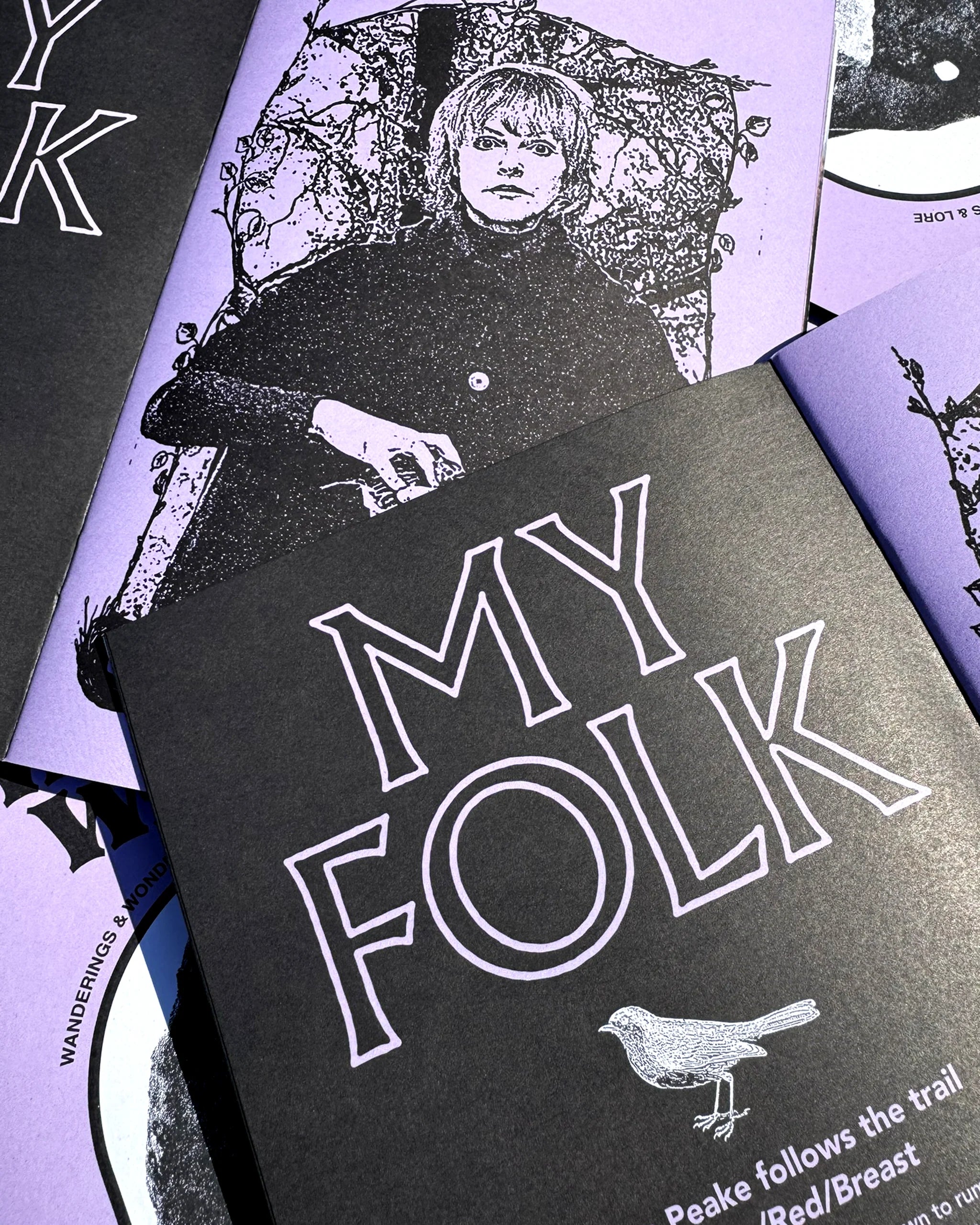 Stack of Weird Walk Zine Issue 8 booklets with folklore-inspired black and purple cover art; indie magazine collection.