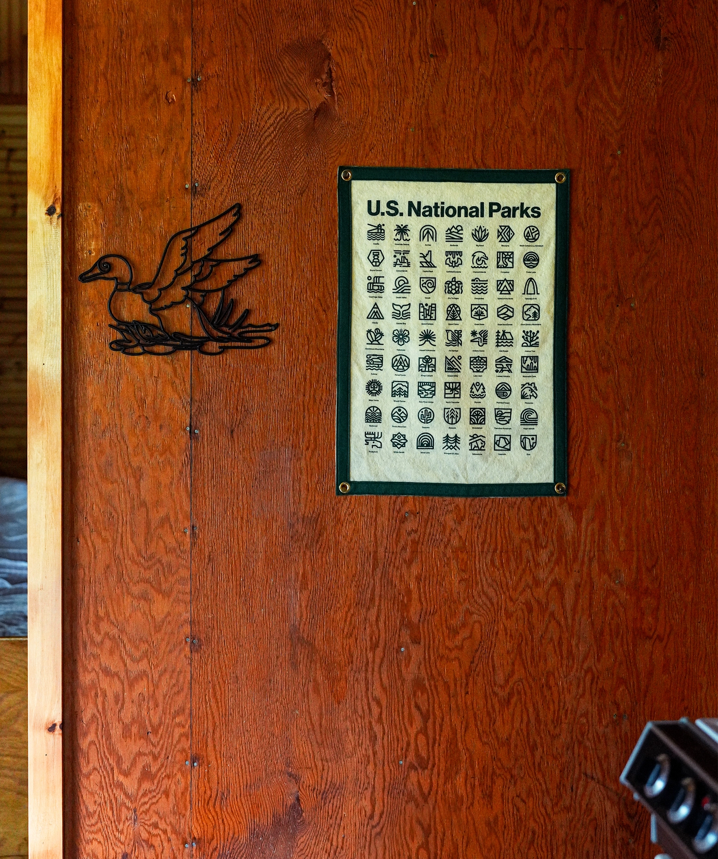 Oxford Pennant National Parks Camp Flag by Steve Wolf on wooden wall, next to vintage metal duck decor, rustic home accent.