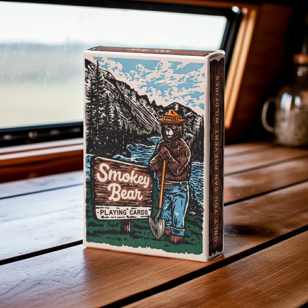 Forager Provisions LTD Smokey Bear playing card deck featuring retro forest illustration on a wooden table.