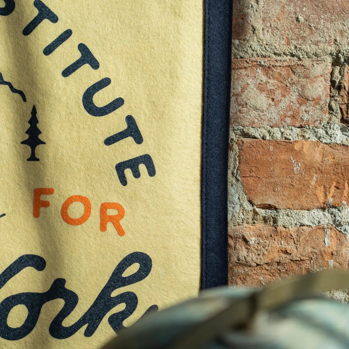Oxford Pennant "There Is No Substitute For Hard Work" camp flag displayed near rustic brick wall, vintage home office decor.