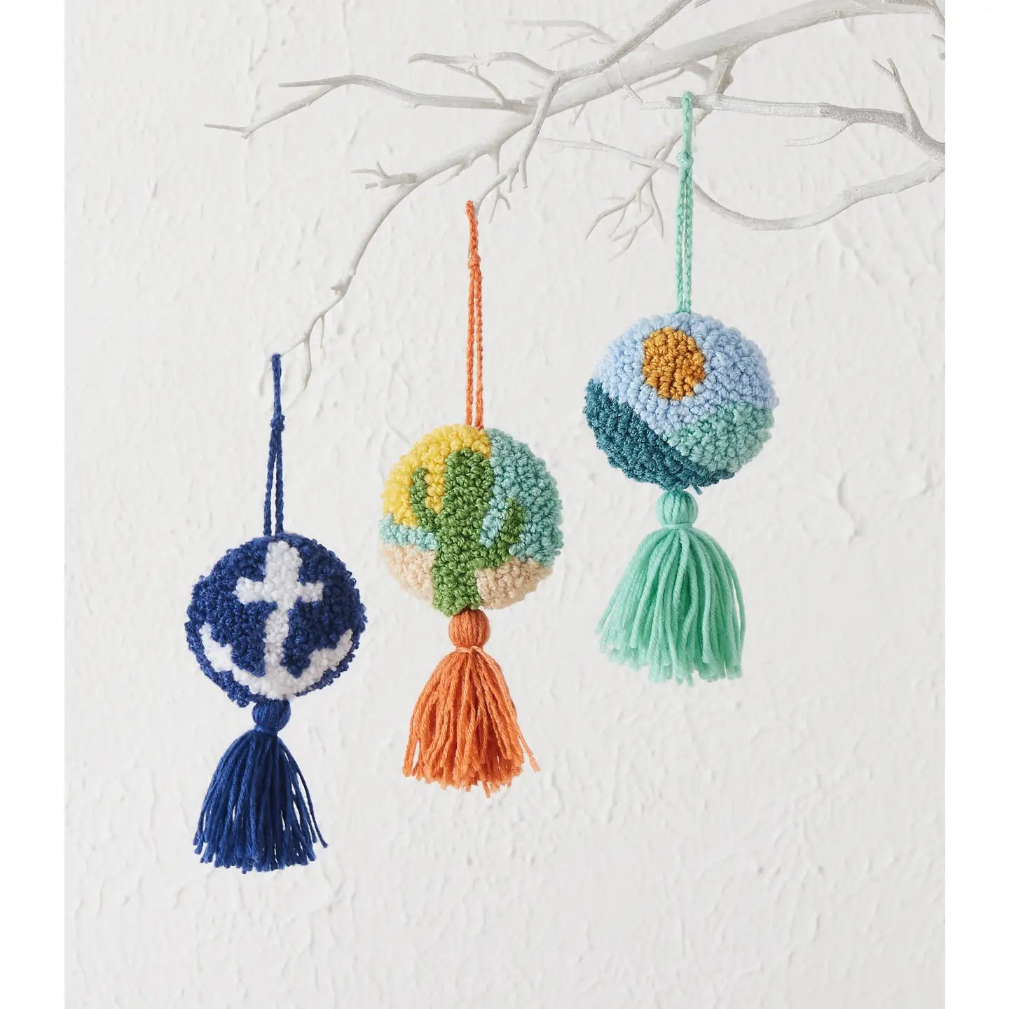 The Peking Handicraft Hanging Cactus Decoration is a circular keychain featuring a woven green cactus on a desert background. It comes with an orange loop and matching tassel, includes a poly hook for easy attachment, and has blown-in filled padding for added durability.