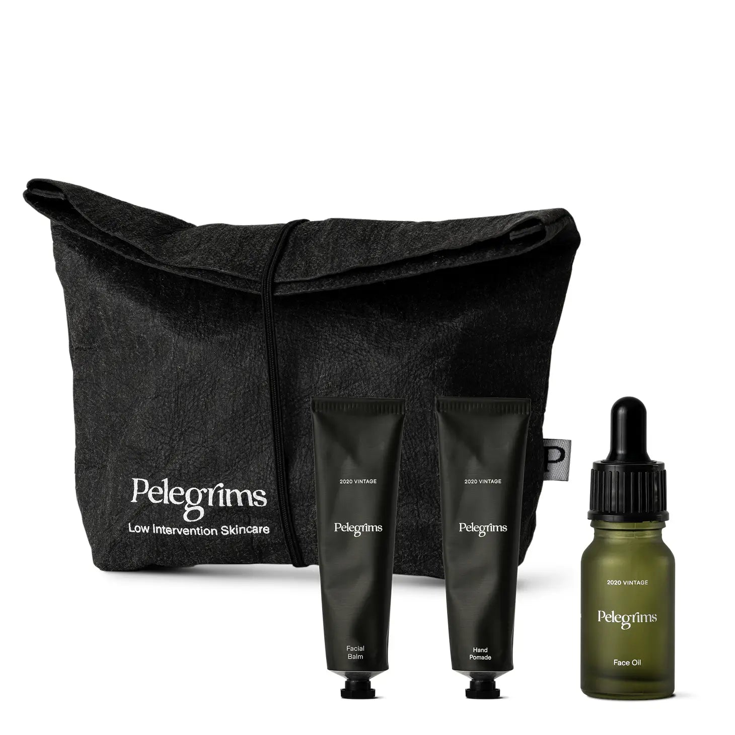 A black toiletry bag featuring Pelegrims branding, containing travel sizes of facial balm and hand pomade, along with a dropper bottle of facial oil infused with Pinot Noir Grape Extract, known as the Pelegrims Exploration Set.
