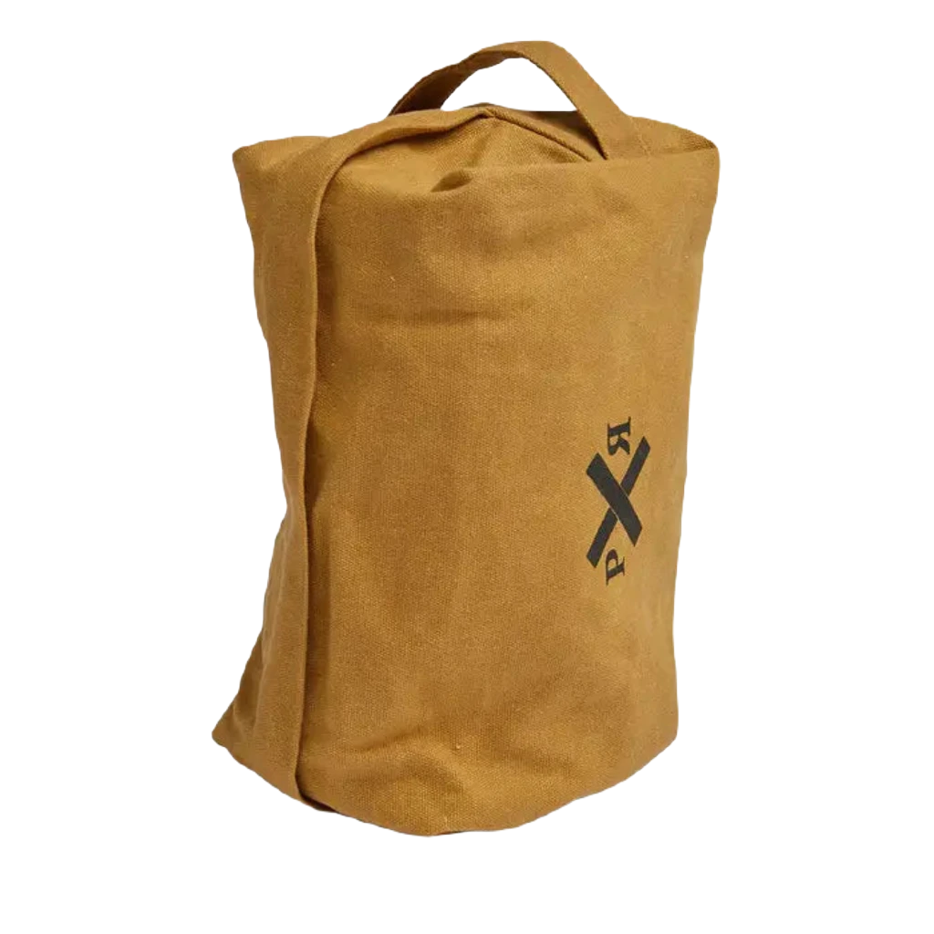 The Pony Rider Slow Road Waxed Canvas Toiletry Bag in Clay is standing upright, showcasing a black crossed arrows graphic on its tan canvas front. It features a short handle at the top and a secure zip closure. Made in India, this versatile piece can double as a stylish grooming bag.