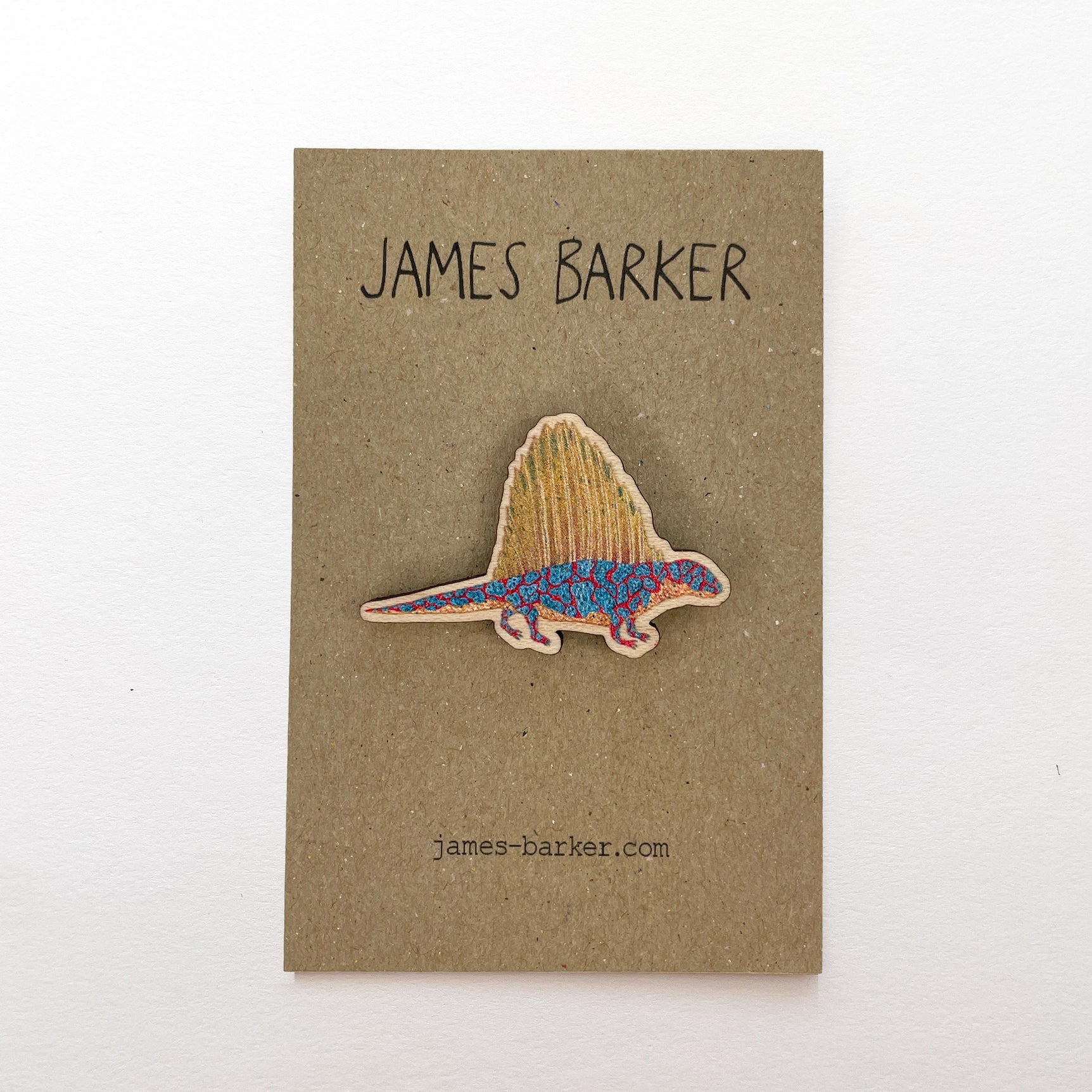Colorful eco-friendly James Barker Dimetrodon dinosaur wooden pin on a branded card; unique prehistoric gift for collectors.