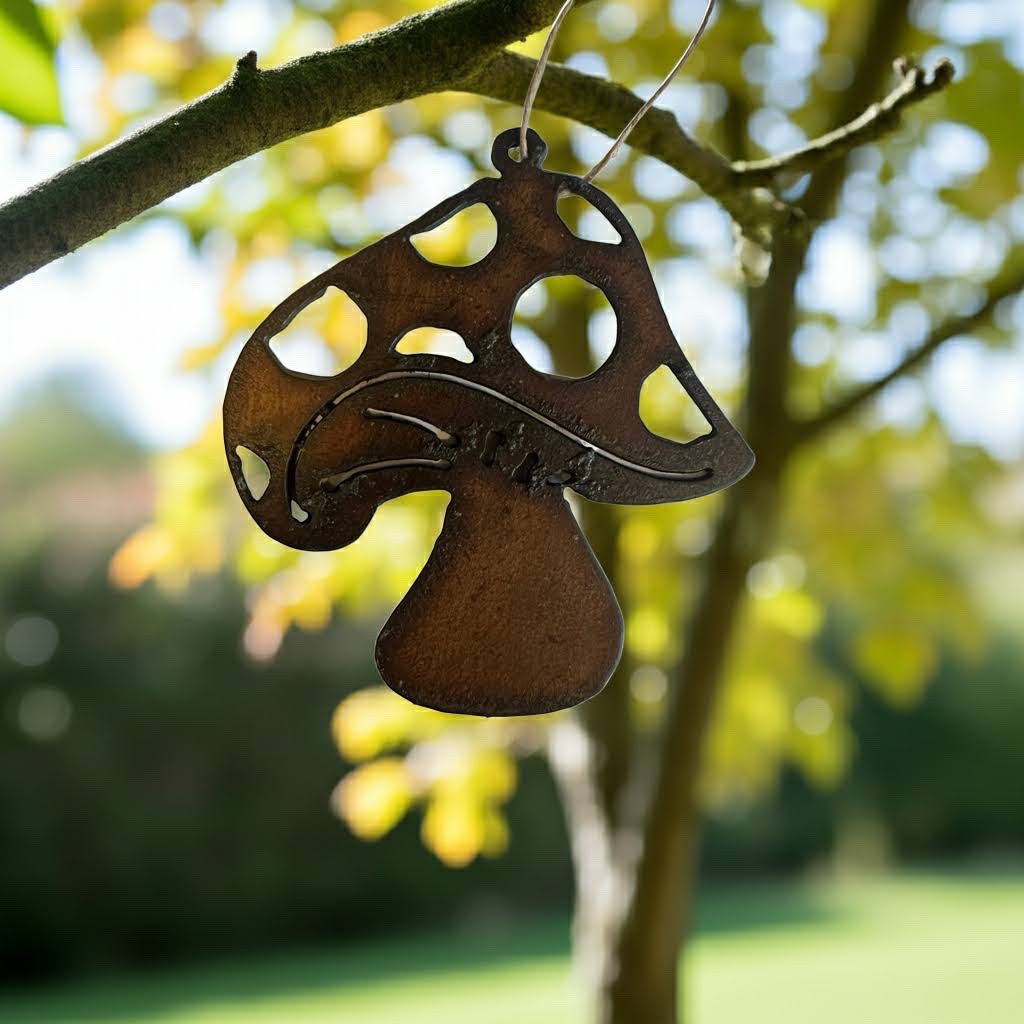 Forager Provisions LTD whimsical mushroom hanging decoration made of rustic hand-cut steel, displayed on a tree branch.