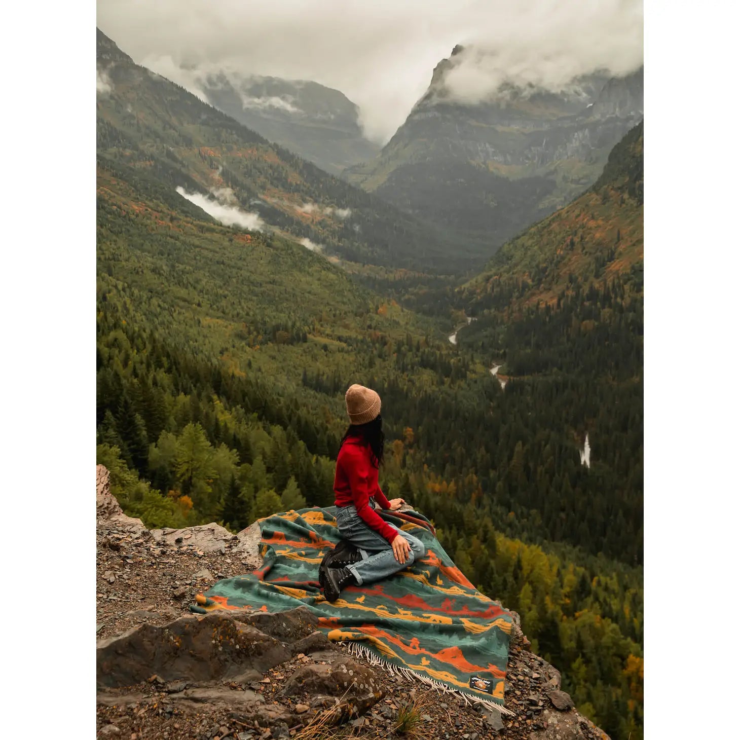 Introducing the Sackcloth & Ashes Smokey Bear Blanket - Smokey Wild: a uniquely crafted blanket featuring a vibrant forest and wilderness pattern adorned with mountains, wildlife, and trees in blue, red, and yellow hues. This special piece promotes wildfire prevention while being thoughtfully made from recycled materials.