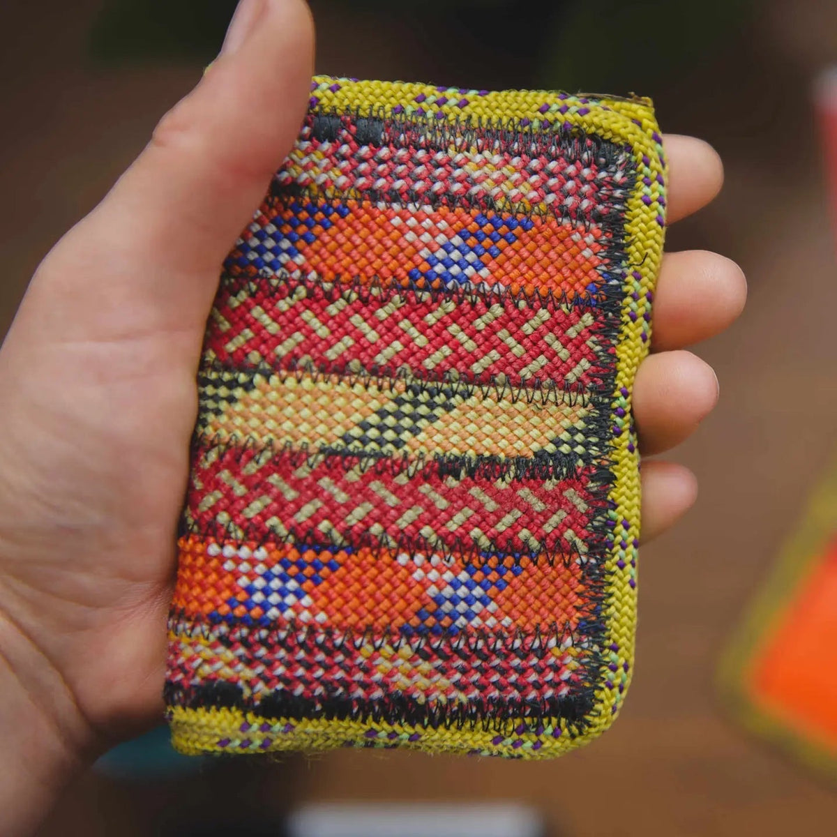 Hand holds Scavenger Upcycled Climbing Rope Wallet—Fire, with yellow border. Eco-friendly, artisan climbing wallet style.
