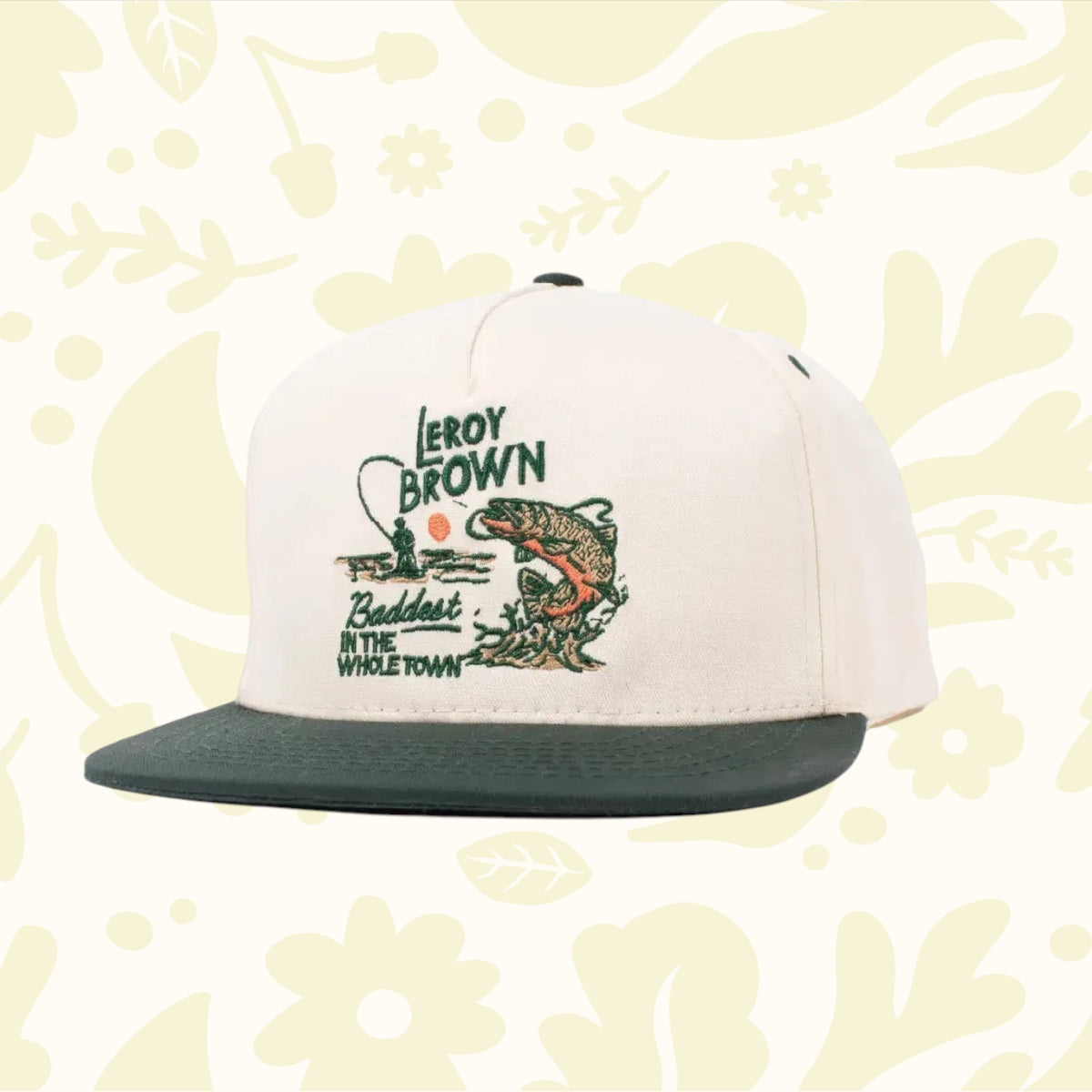 The Sendero Provisions LeRoy Brown Cap is a white and green cap made from durable cotton canvas, featuring an embroidered design of a fish and the text "Leroy Brown, Baddest in the Whole Town.