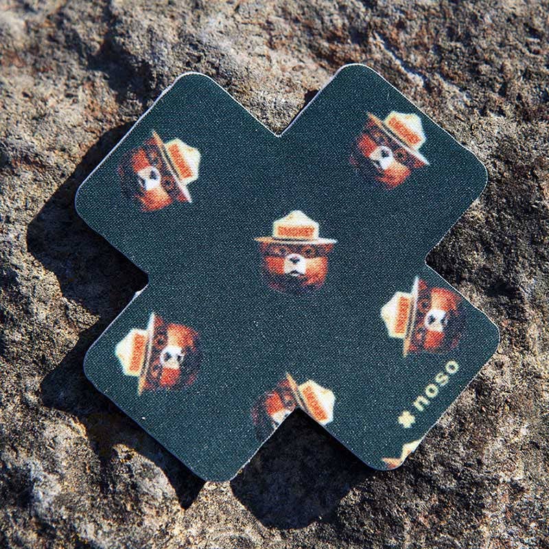 Forager Provisions LTD Smokey Bear Head Toss x NoSo repair patch on a textured rock surface.