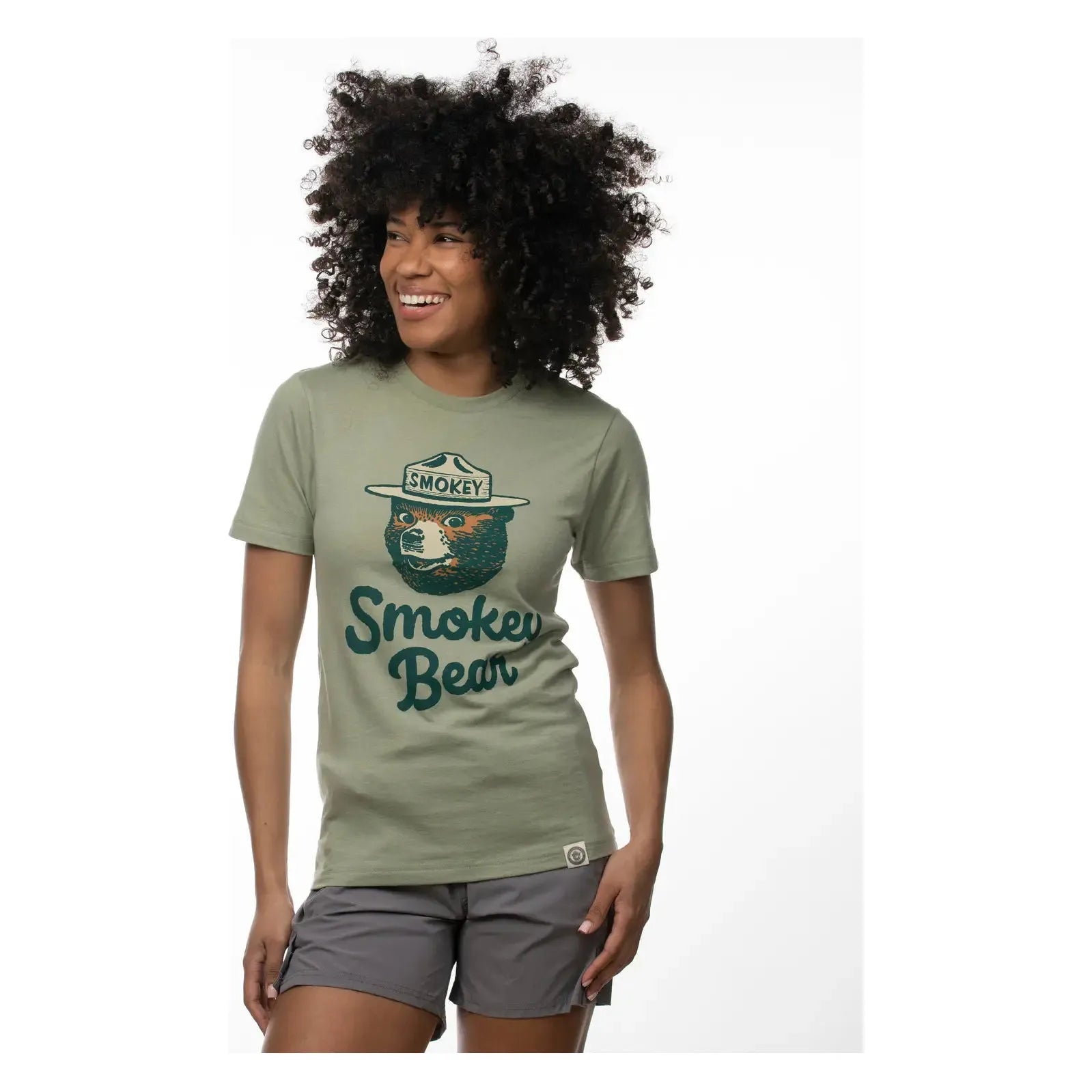 The Landmark Project Heritage Smokey Bear T-Shirt in Bay Leaf features a graphic of Smokey Bear wearing a ranger hat, with the text "Smokey Bear" below. This sustainably made tee boasts vintage colors that enhance its timeless appeal.