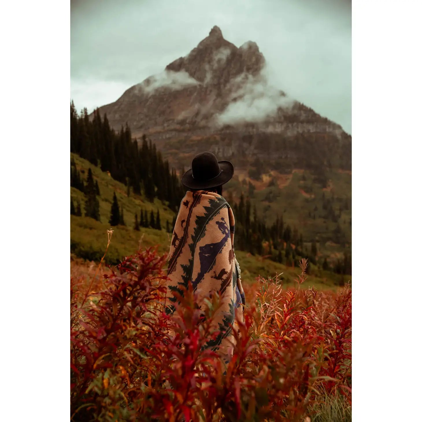 A Sackcloth & Ashes Smokey Bear Blanket - Smokey Dungaree, featuring woven rows with wilderness scenes of trees, mountains, bears, deer, and human figures in neutral tones.