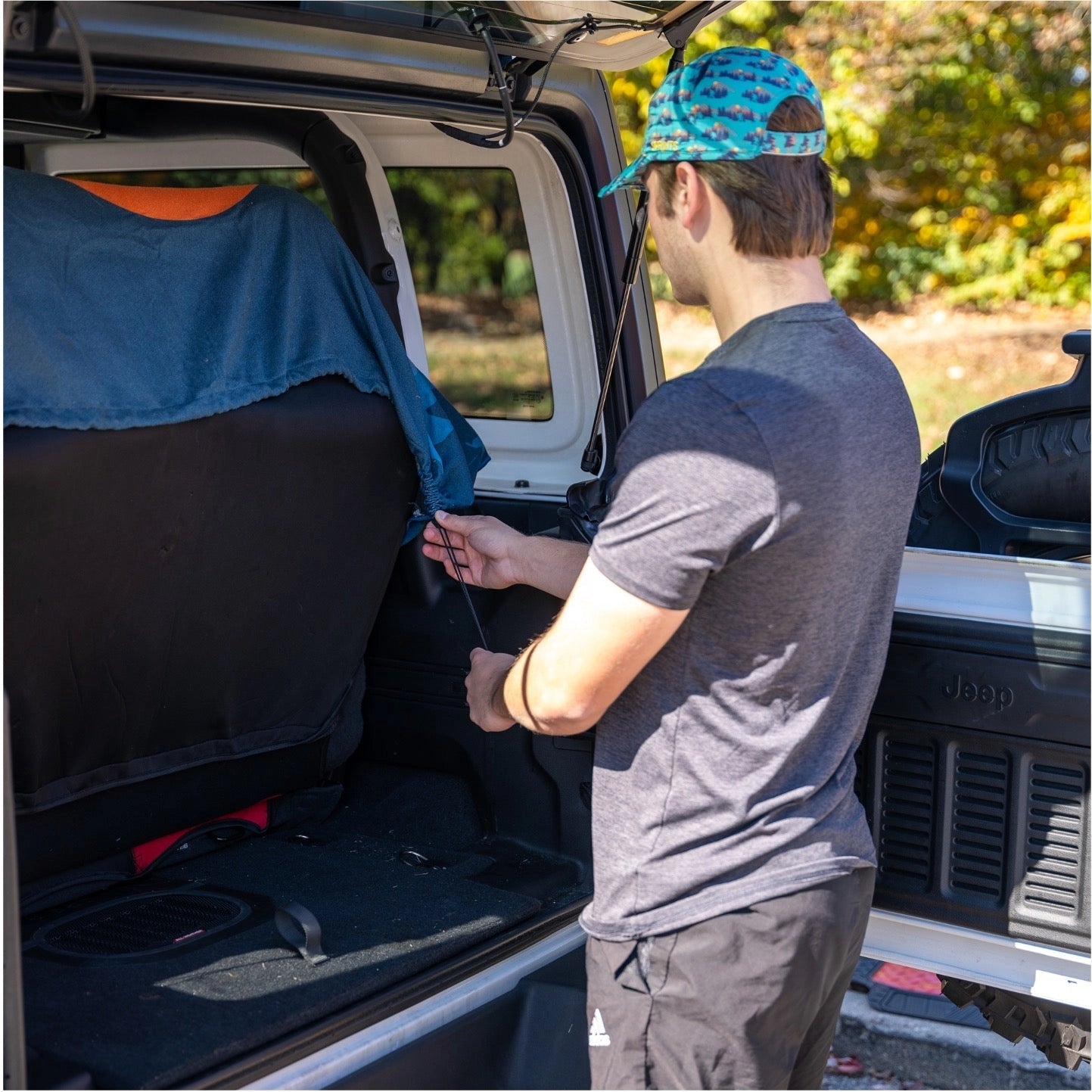 Forager Provisions LTD Sprints Bigfoot print towel car seat cover being installed in a Jeep trunk by a man.