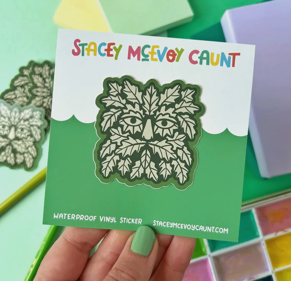 Sticker with leaf design held by a hand on a colorful background