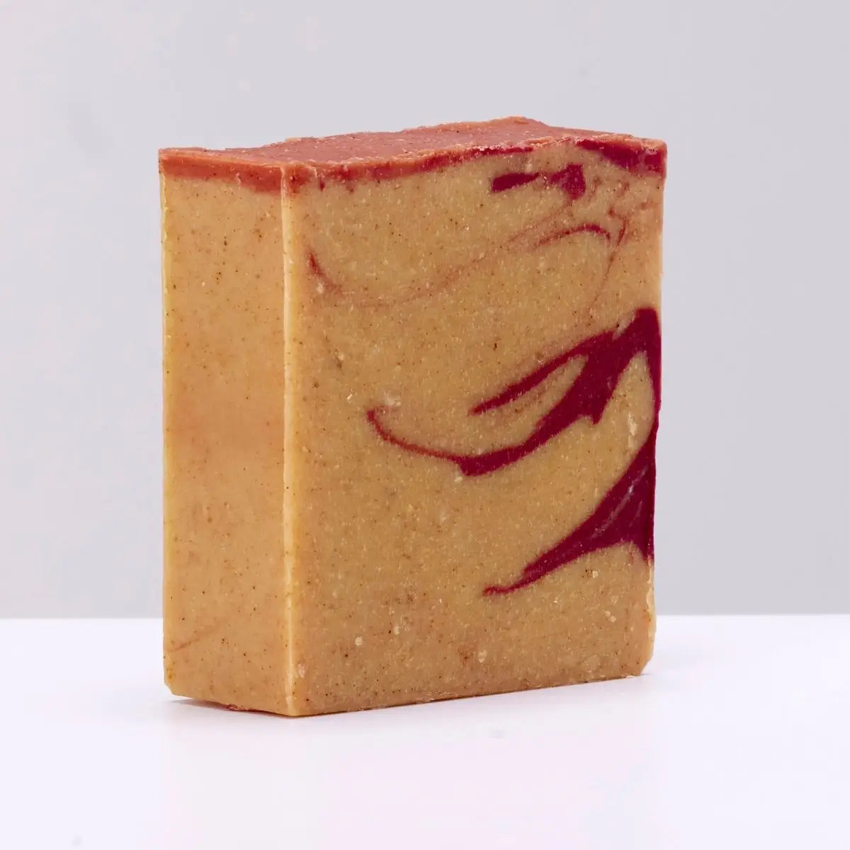 Rectangular handcrafted soap bar with tan base, bold red swirls, and a red top—The Black Stuff Soap: Celtic Tiger artisan soap.