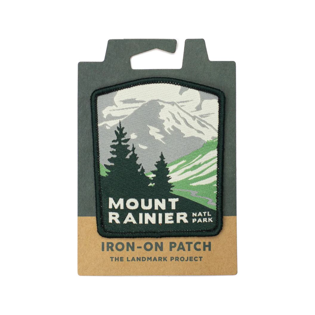 The Landmark Project Mount Rainier National Parks Patch features an illustration of Mount Rainier and trees, labeled "Mount Rainier Natl Park." It's perfect for outdoor adventures and is packaged sustainably.
