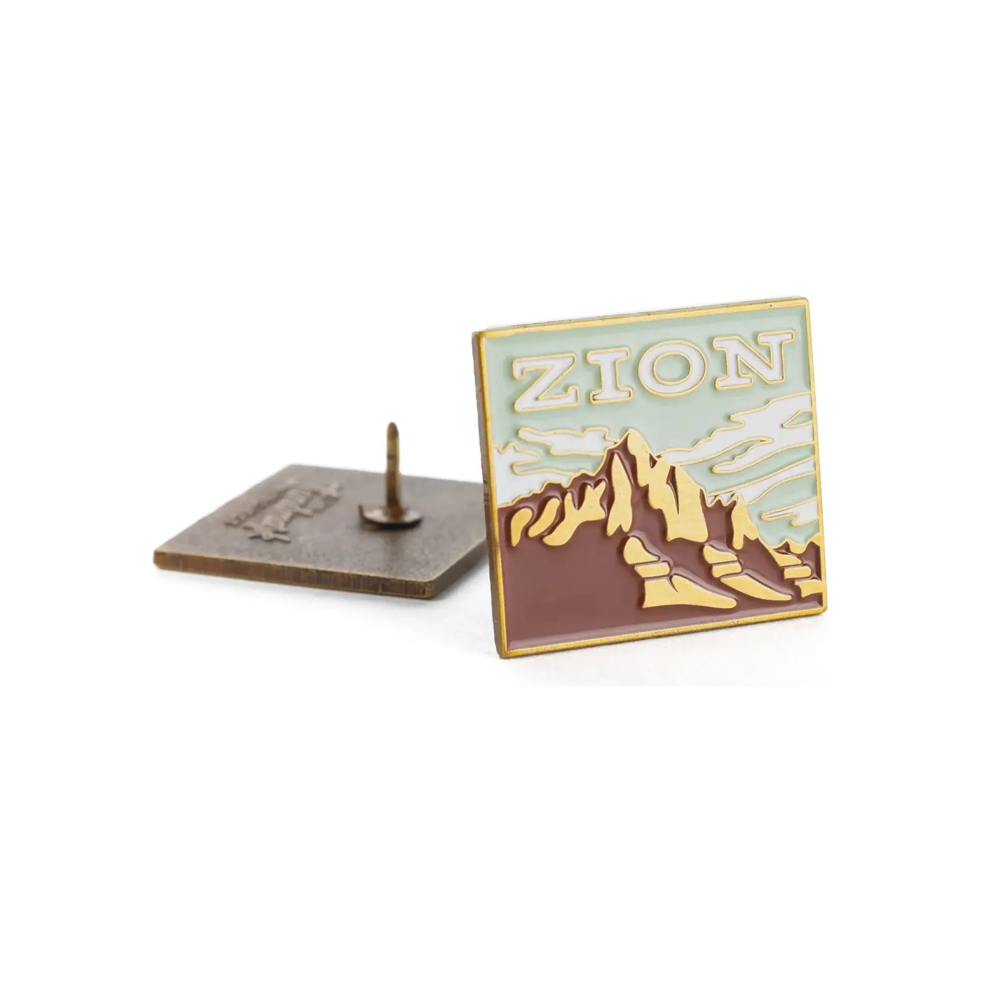 The Landmark Project Zion Pin is an enamel pin featuring a mountain landscape, attached to a cardboard backing with the text "Landmark Enamel Pin" and packaged sustainably.