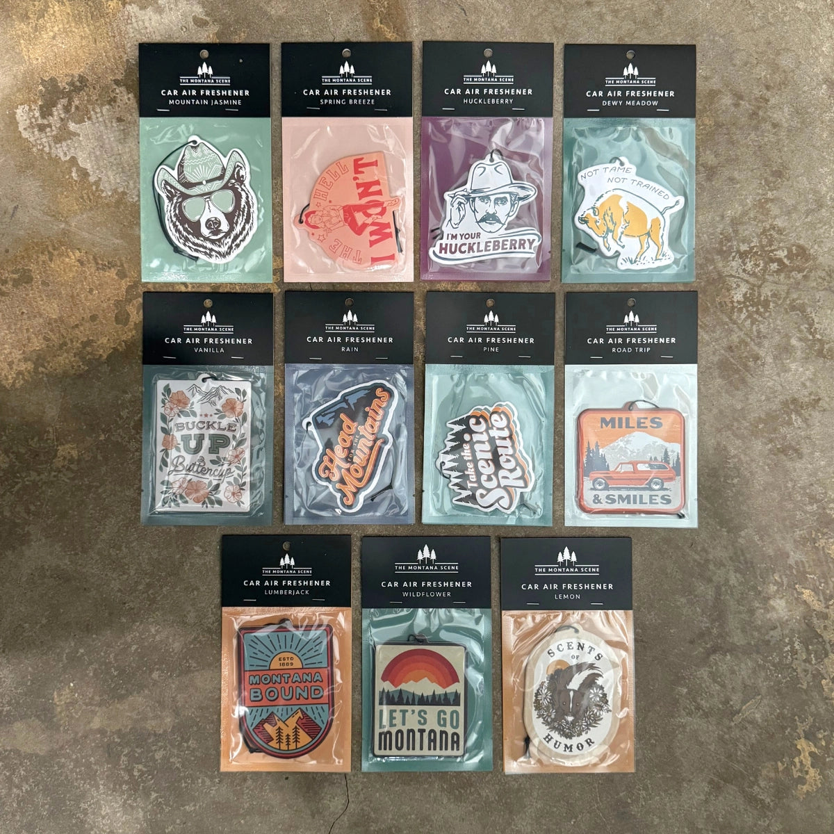 Twelve Montana Scene Dewy Meadow Car Air Fresheners neatly arranged in three rows on concrete, perfect for fresh car scent.