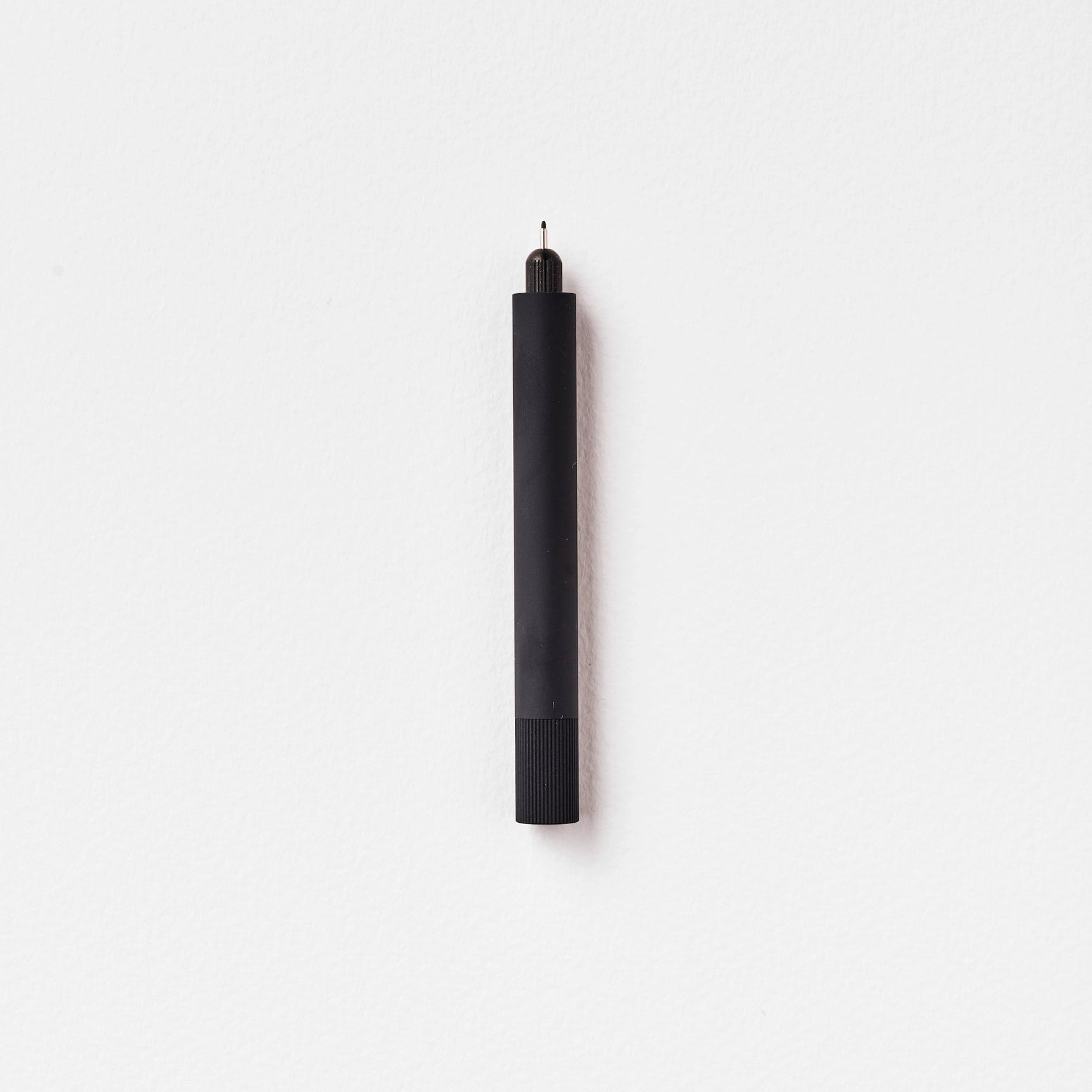 Tom’s Studio Lumos Mini Pen Matte Black, featuring a knurled grip, stands upright on a clean white background for modern style.